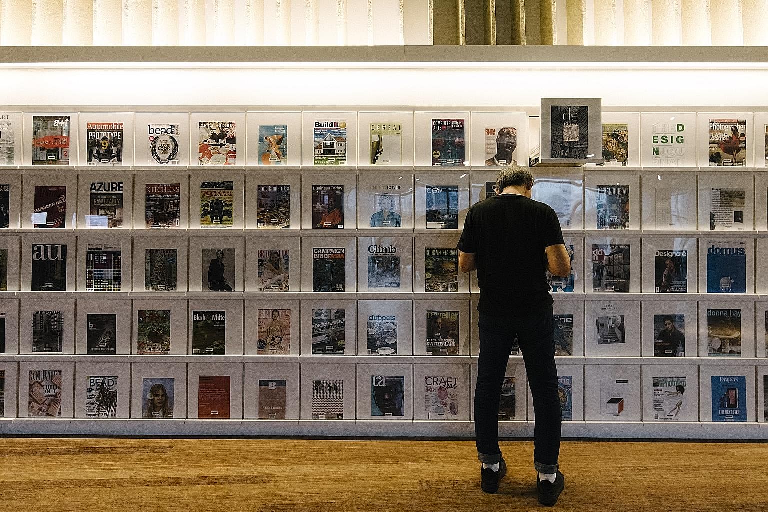 A reader at library@orchard at the magazine wall. Located at Orchardgateway, the library has a focus on design.
