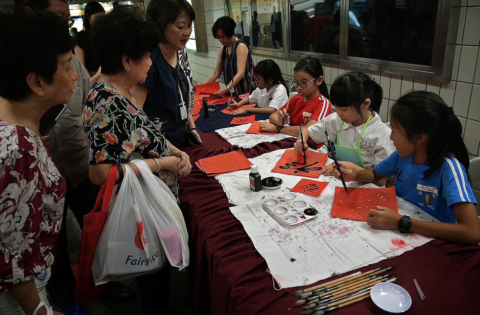 Pupils from Pei Chun Public School demonstrating the art of Chinese calligraphy at Toa Payoh MRT station yesterday as part of the Chinese New Year festivities. The pieces of artwork were then given to members of the public. The activity was organised