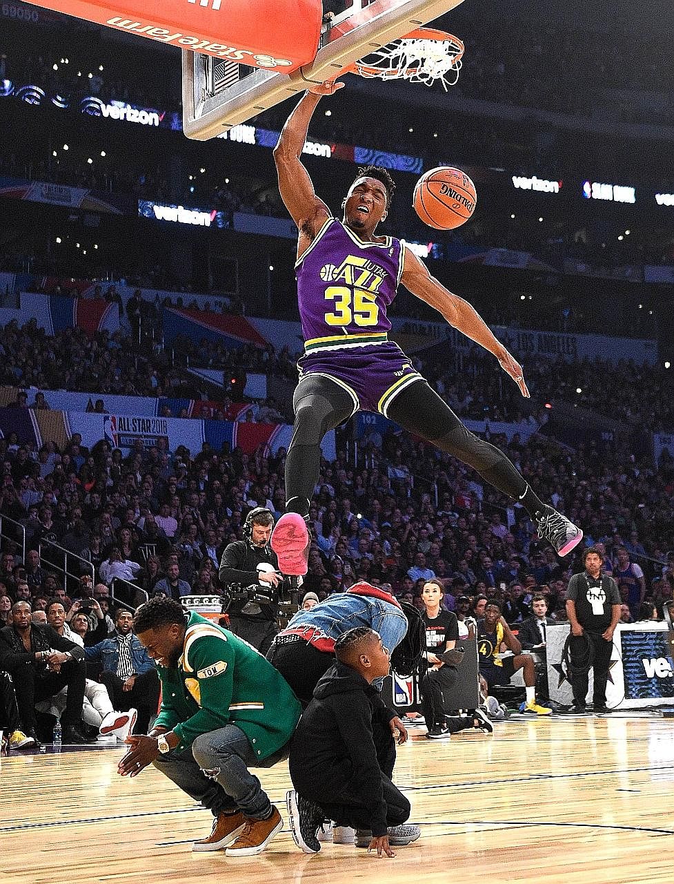 Donovan Mitchell of the Utah Jazz, donning a retro Darrell Griffith Jazz jersey complete with short shorts, soars and dunks over his sister Jordan, American comedian Kevin Hart and his 10-year-old son Hendrix, in his second dunk of the NBA Slam Dunk 