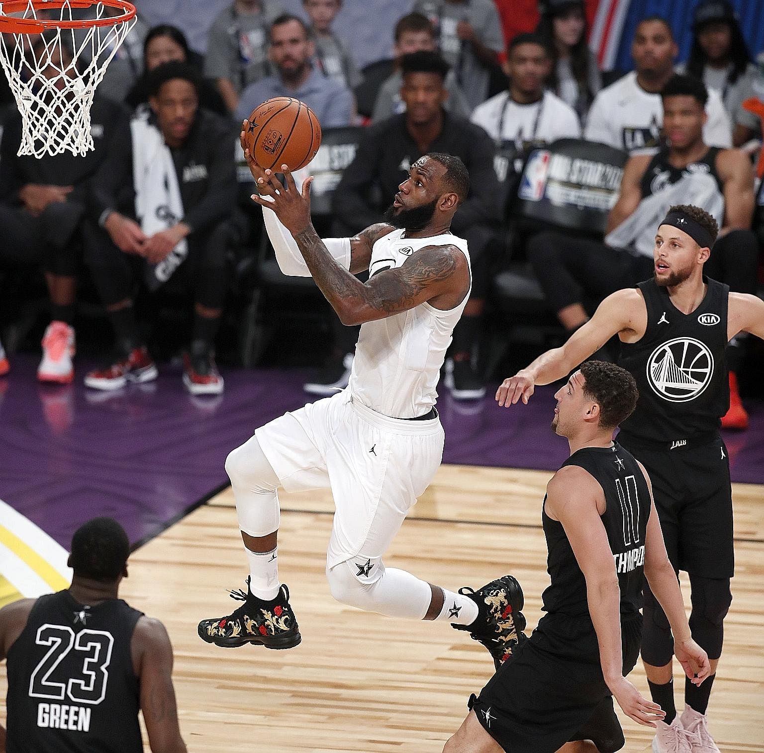LeBron James going up for a shot after getting past (from left) Draymond Green, Klay Thompson and Stephen Curry in Sunday's All-Star Game.