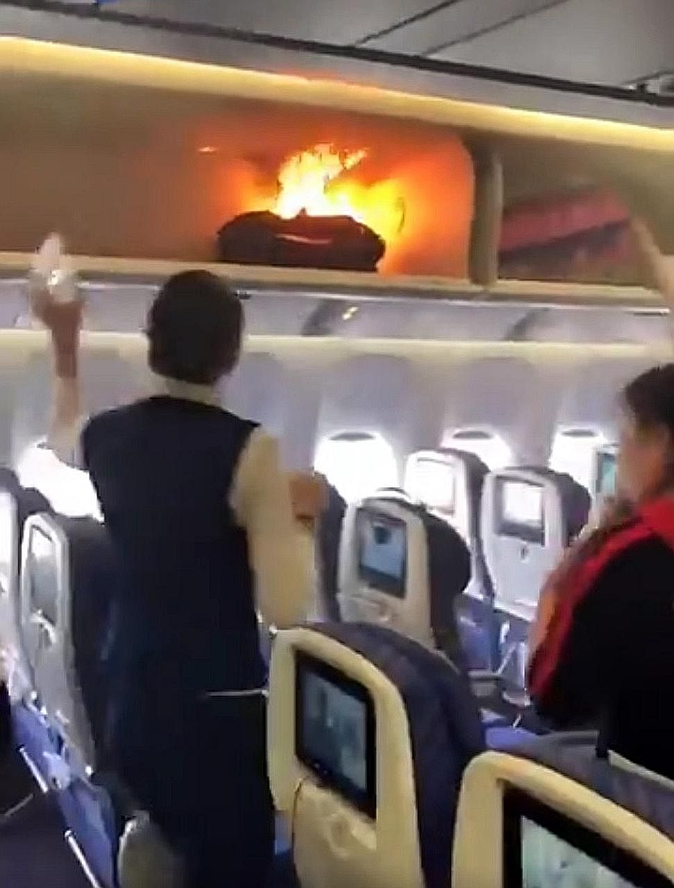 A flight attendant trying to douse the flames from a passenger's cabin bag. The incident on the China Southern Airlines plane took place as passengers were boarding in Guangzhou.