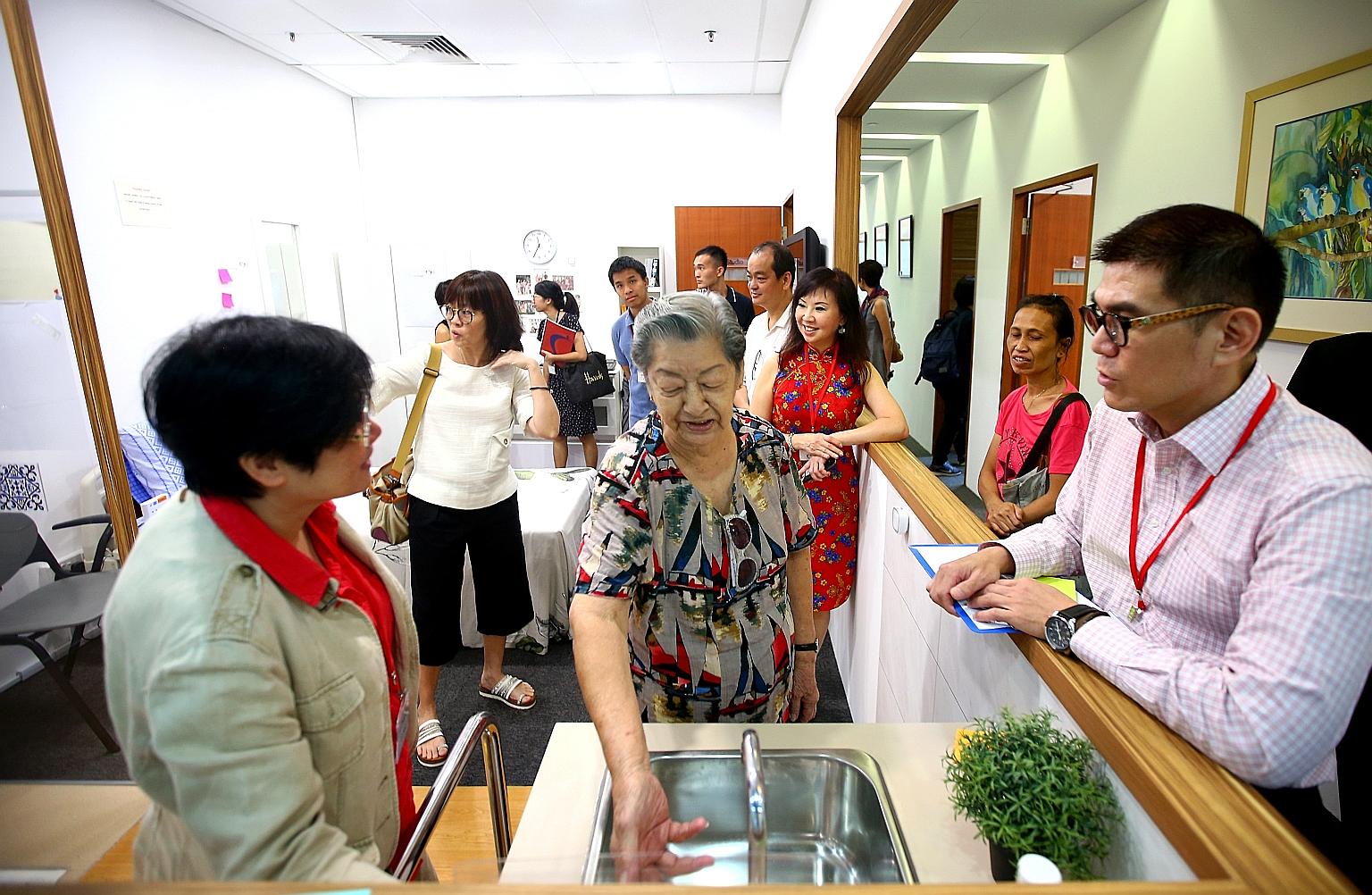 Madam Koh Seow Kim, 86 (centre), getting a hands-on tour of a mock-up studio flat at the Centre For Seniors open house in Bishan yesterday. The centre will be holding roadshows every two months to inform seniors about the new website, and teach less 