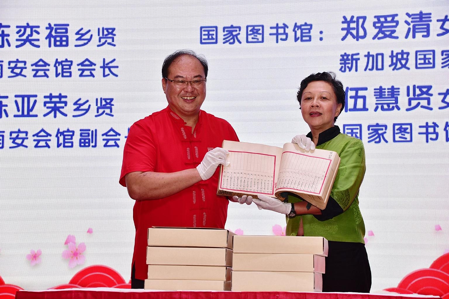 Mr Tan Aik Hock, chairman of the Singapore Lam Ann Association, and National Library Board deputy chief executive Tay Ai Cheng holding one of the seven rare account books on Hong San See temple.