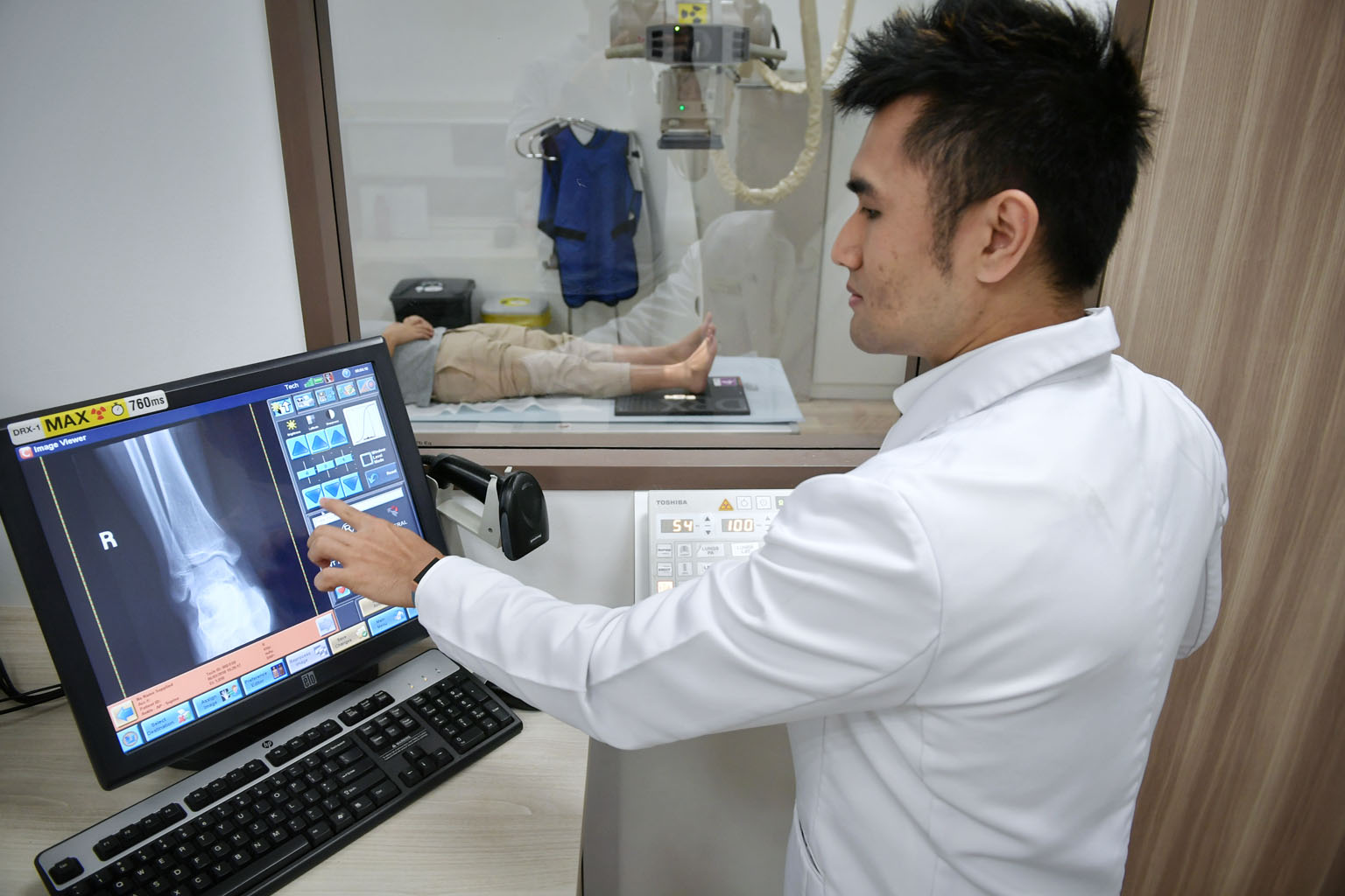 NHG radiographer Harris Abdul Razak using the digital radiography system to process an X-ray image of a patient's ankle at Ang Mo Kio Polyclinic. X-rays can now be done for 120 patients a day "without breaking a sweat", he says, compared to up to 80