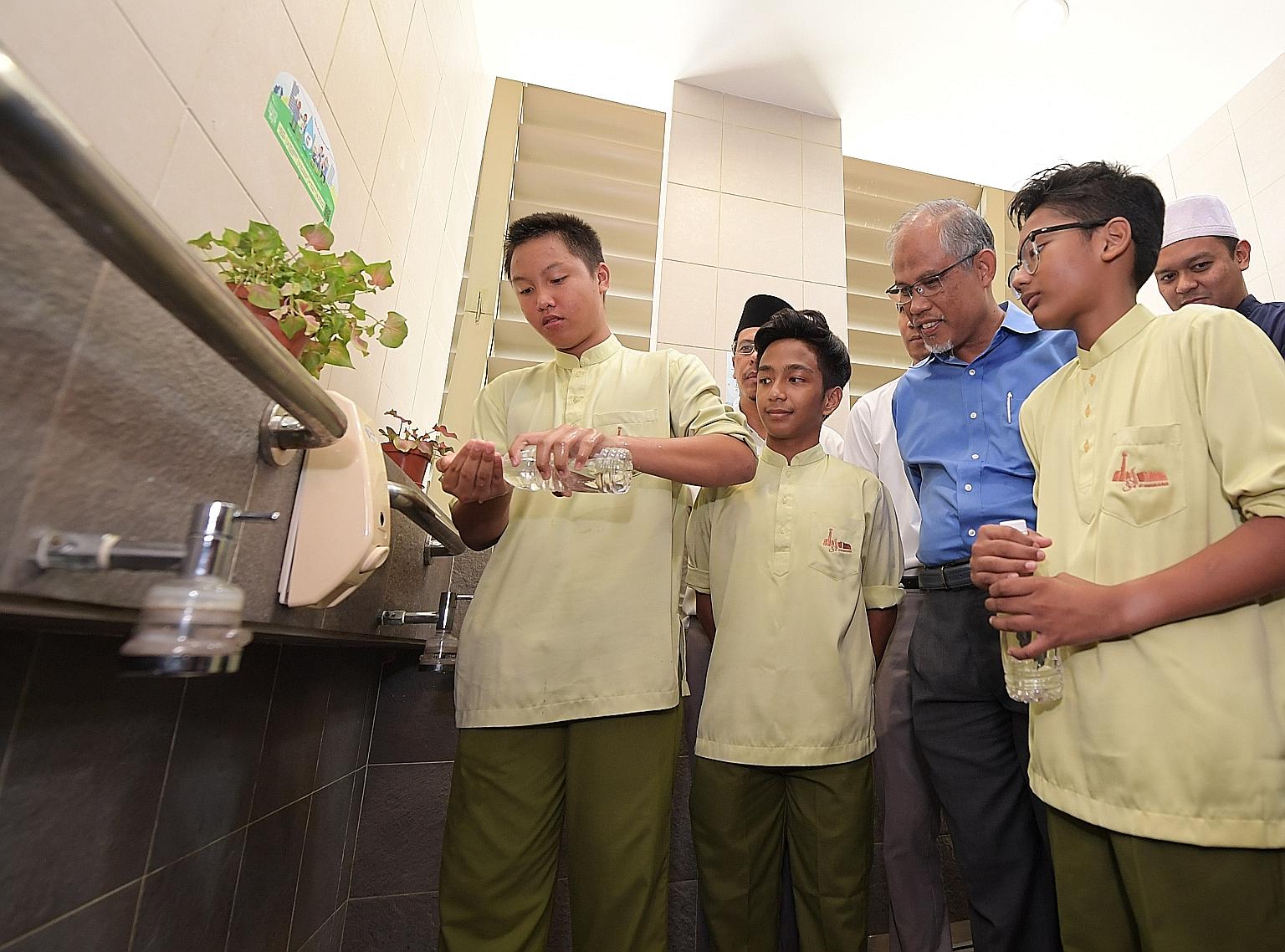 Muhammad Afif Sahernizam, 13, showing Minister for the Environment and Water Resources Masagos Zulkifli how he practises his ablutions in a water-efficient way with a small bottle of water at the Al-Mawaddah Mosque in Sengkang.