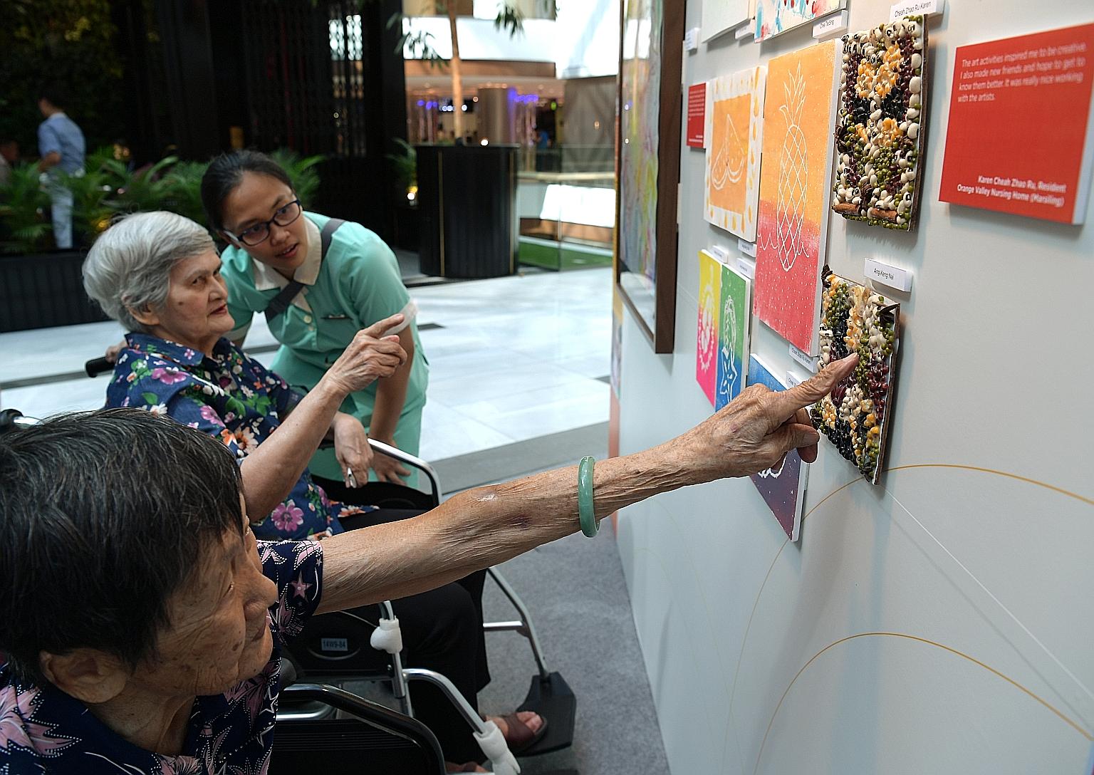 Madam Kwan Ah Geok (foreground), 91, and Madam Joan Oliviero, 82, from Econ Healthcare looking at artworks by other nursing home residents.