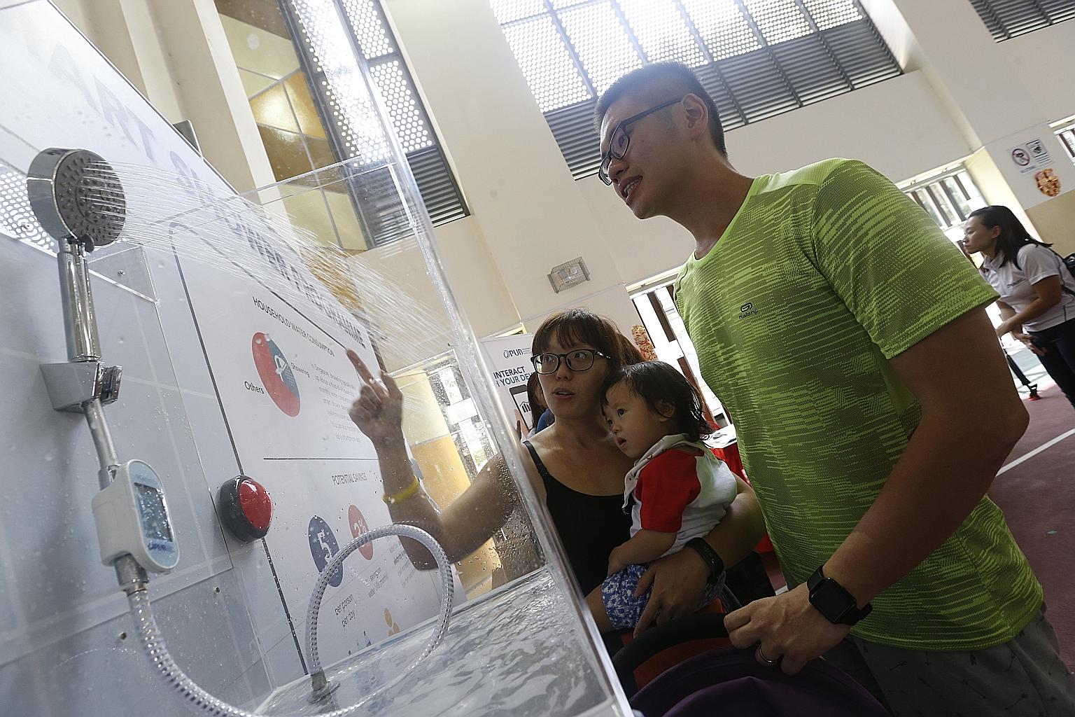 Army regular Joseph Soh, 30, with his 26-year-old wife Caroline Huang, a housewife, and their child Jaylyn checking out the smart shower device. Ms Huang says the device "is a very creative solution because it shows me how much I'm using, something I