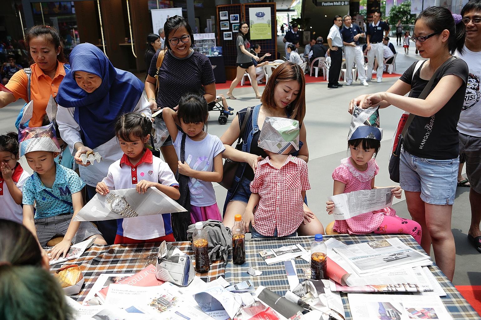 Children learning how to make hats out of newspapers at the Just-One-Earth Day carnival at Our Tampines Hub yesterday. The carnival offered children and their parents hands-on activities to engage them on environmental issues.