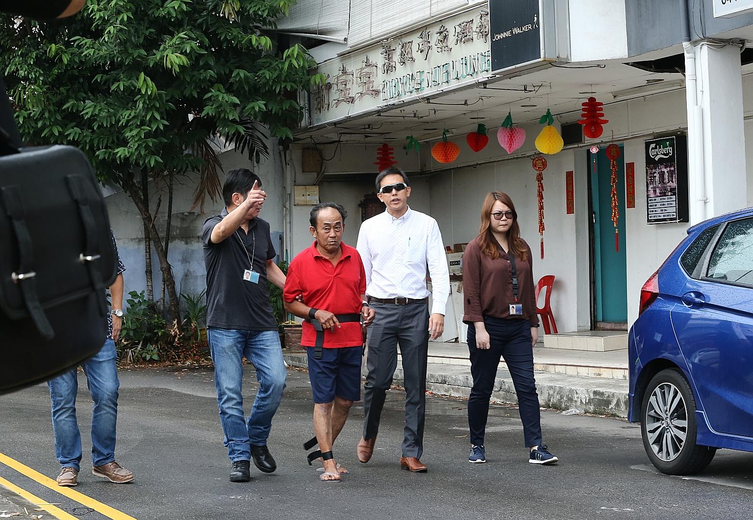 Seow Lam Seng being escorted by officers outside Sin Po Po bar, seen with the old-fashioned neon sign, in Tanjong Katong Road yesterday. It was the scene of a shooting incident 38 years ago, when Lee Ah Fatt drew his pistol on police officers and Seo