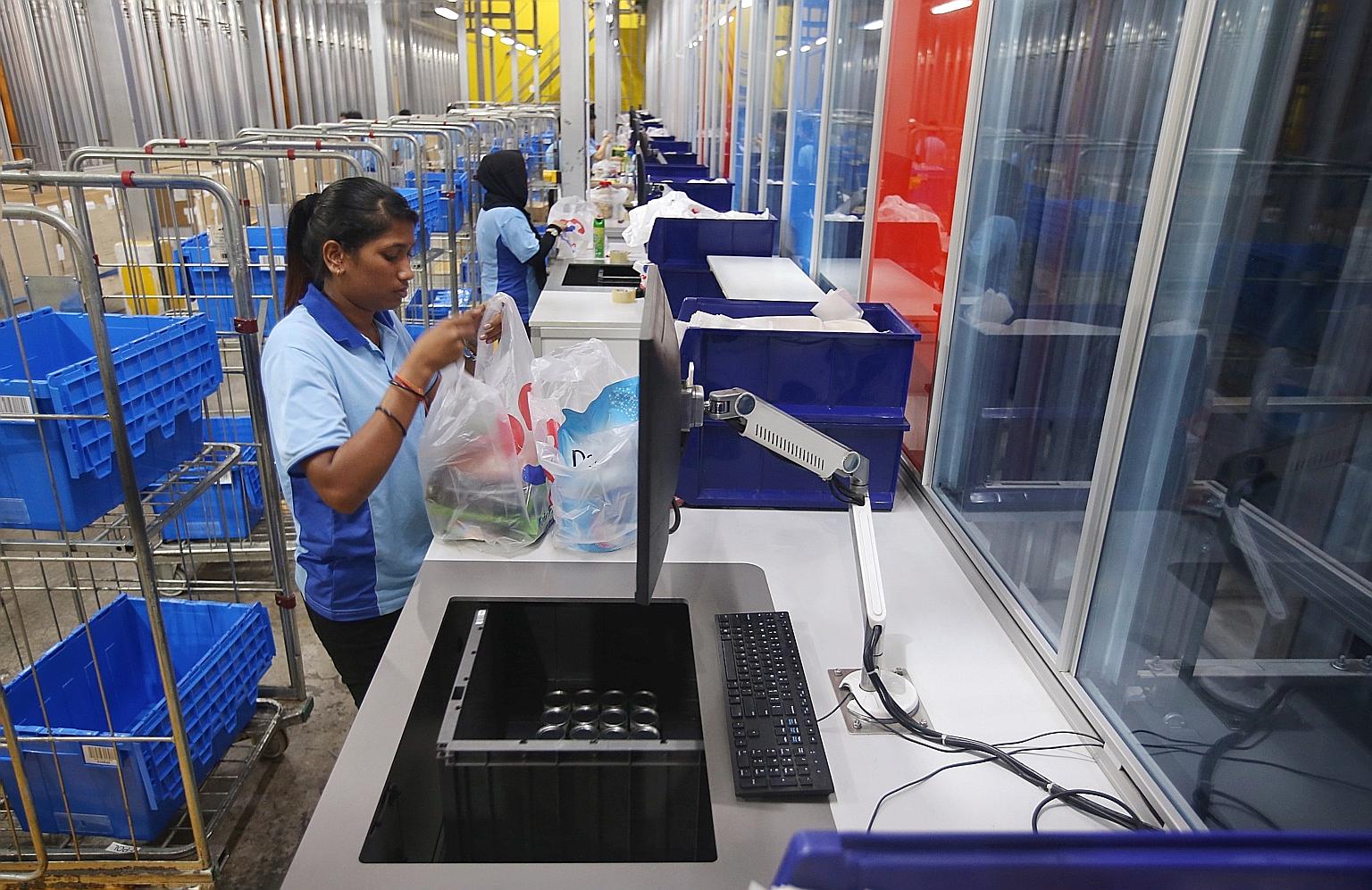 Pickers at the FairPrice Hub distribution centre bagging items for online orders. The new system is four times faster than the old one, which required pickers to retrieve items manually.