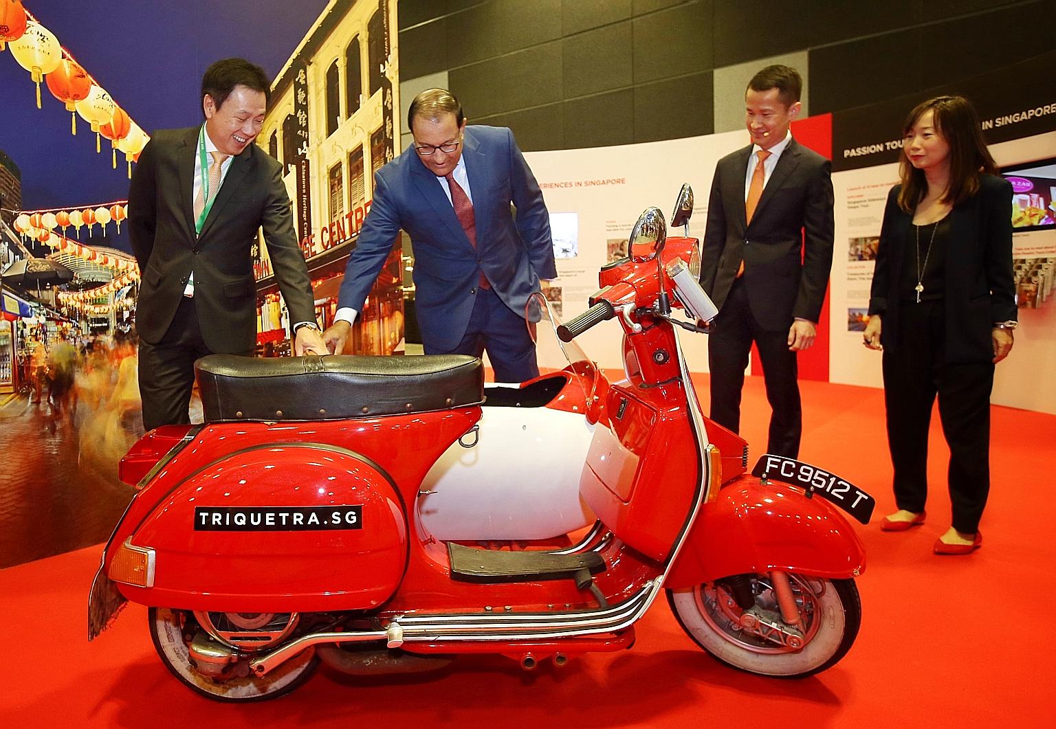 Minister for Trade and Industry (Industry) S. Iswaran looking at a vintage Vespa with a sidecar at the marketing and technology showcase at the Tourism Industry Conference 2018. With him are (from left) STB chairman Chaly Mah, chief executive Lionel