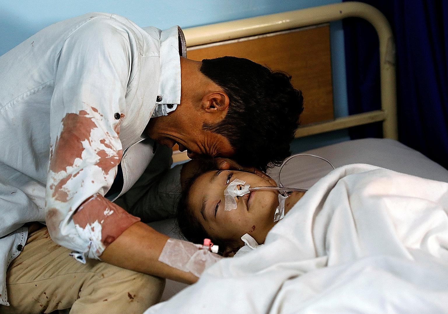 A man crying beside an injured girl at a hospital after the attack in Kabul, Afghanistan.