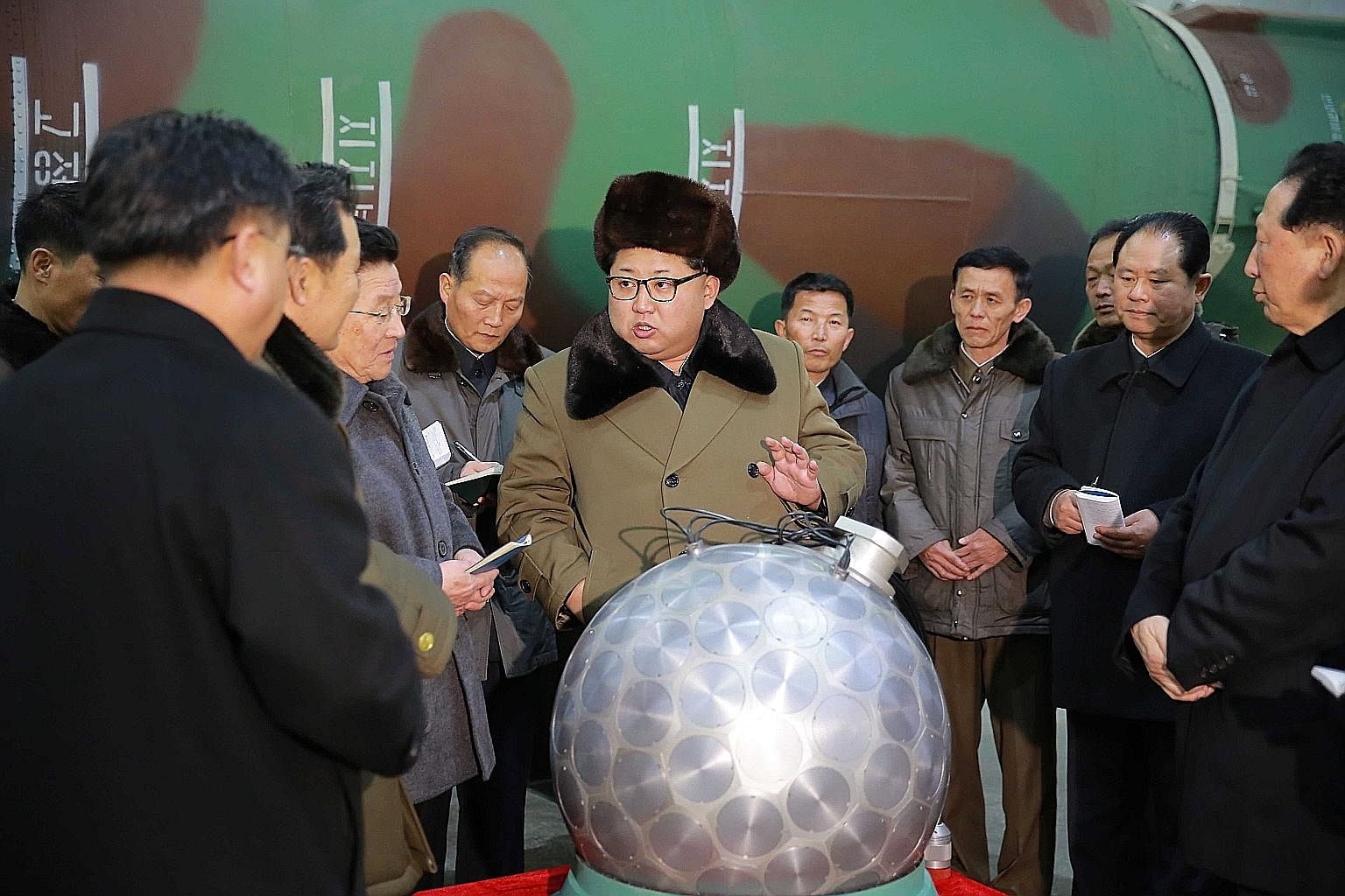 Above: An undated photo released by the Korean Central News Agency (KCNA), the state news agency of North Korea, showing North Korean leader Kim Jong Un (centre) talking with scientists and technicians involved in the research of nuclear weapons, at 