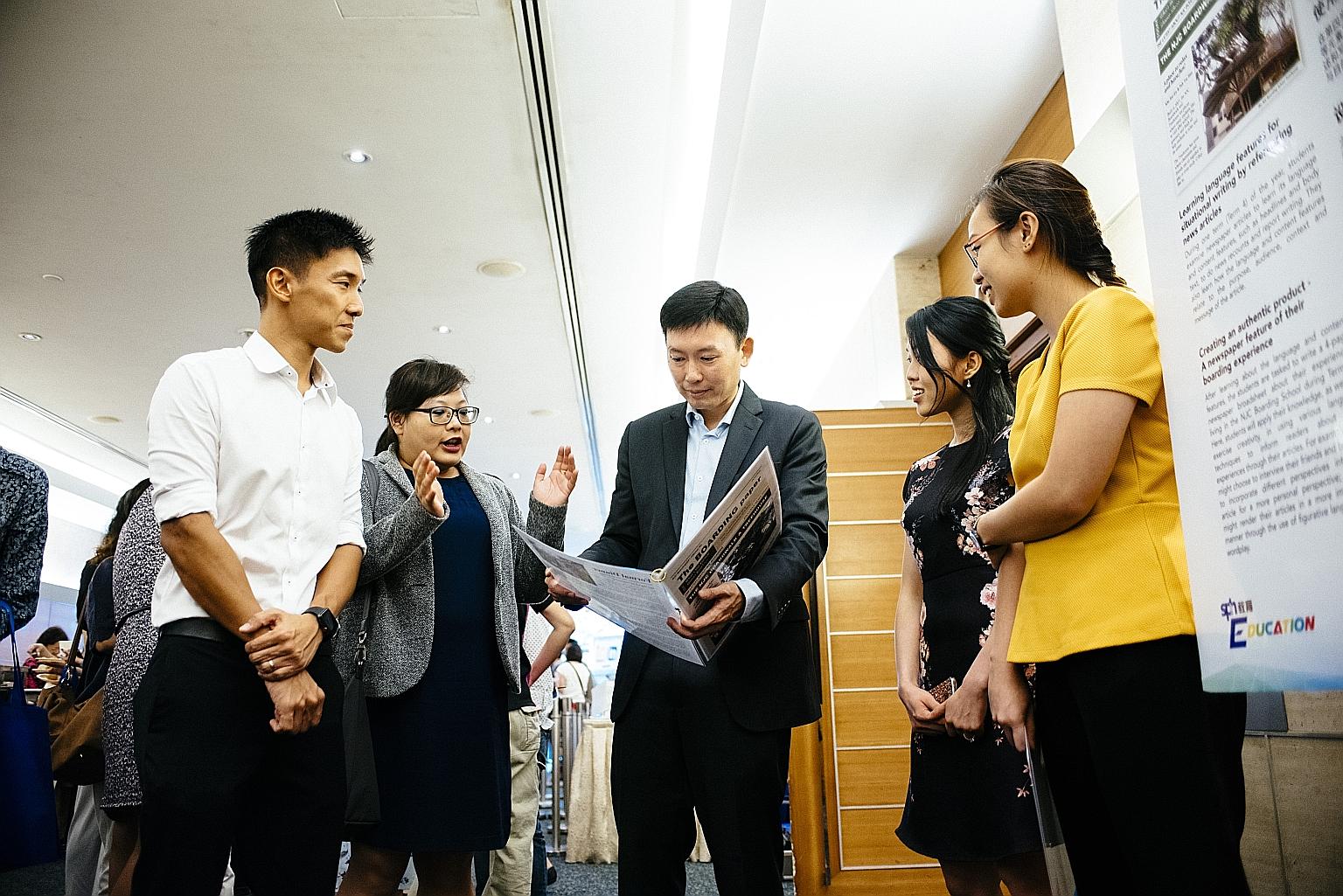 Senior Minister of State for Communications and Information and Health Chee Hong Tat looking at a newsletter put together by students involved in a National Junior College (NJC) project. With him are (from left) The Straits Times Schools teaching spe