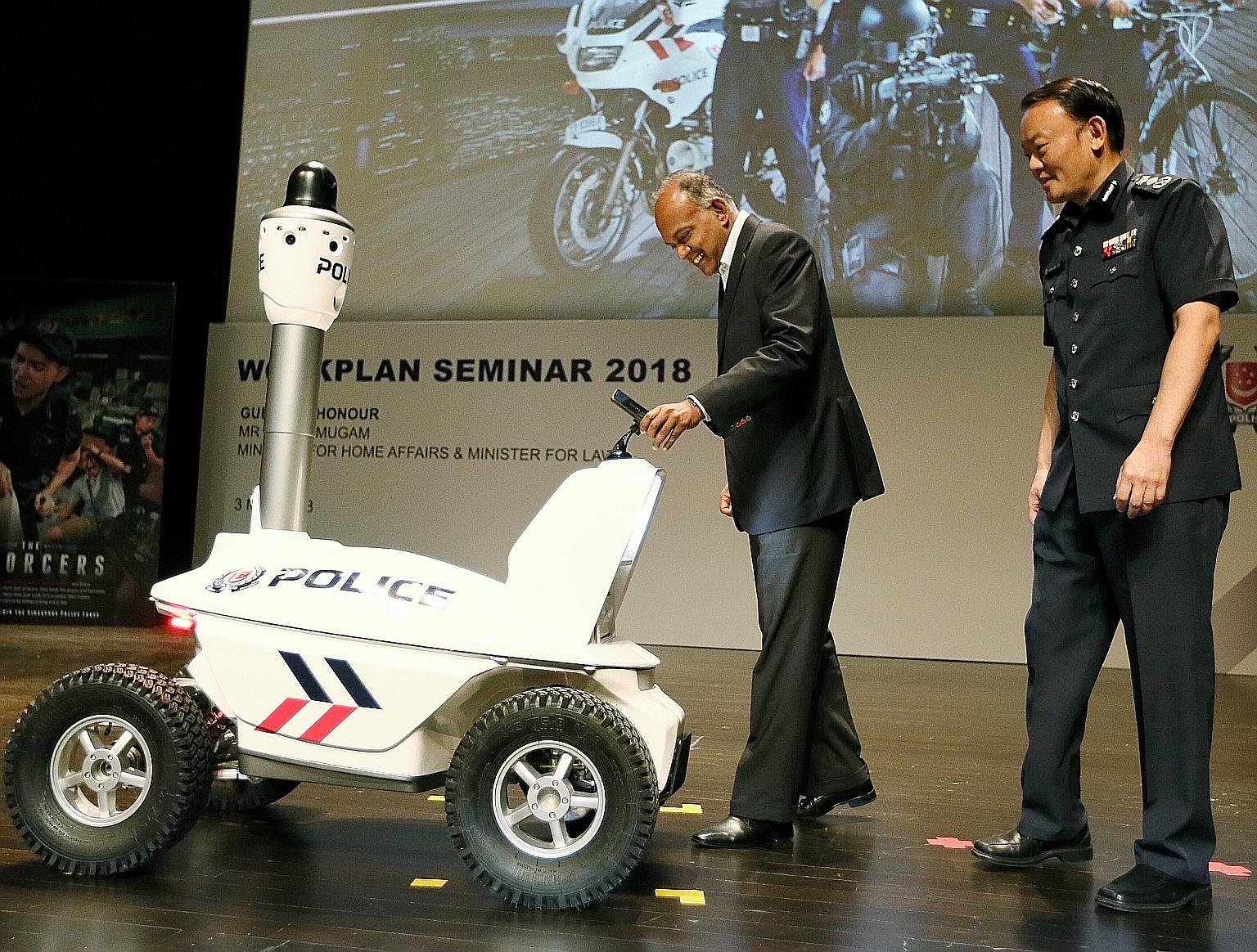 Home Affairs and Law Minister K. Shanmugam, accompanied by Commissioner of Police Hoong Wee Teck, being handed a police smartphone by the S5 Pan-Tilt-Zoom Patrol Robot at the annual police workplan seminar yesterday. The robot and special smartphone