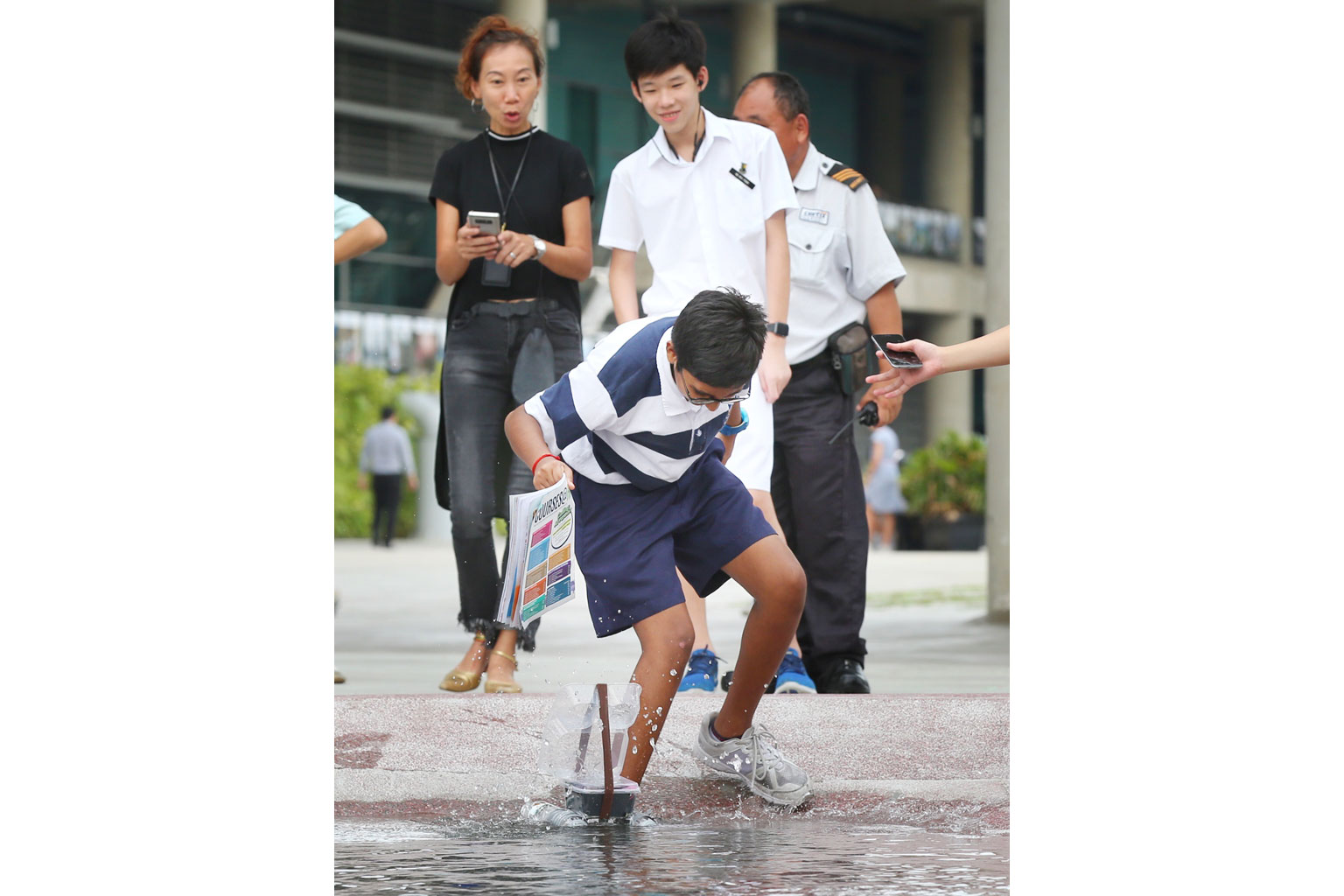 St Andrew's Secondary School student Ashwin Lokesh loses his footing as he tried to use a book to fan his team's robot during the Underwater Robotic Olympiad at Marina Barrage yesterday. The electrical component failed to work and the team was eventu