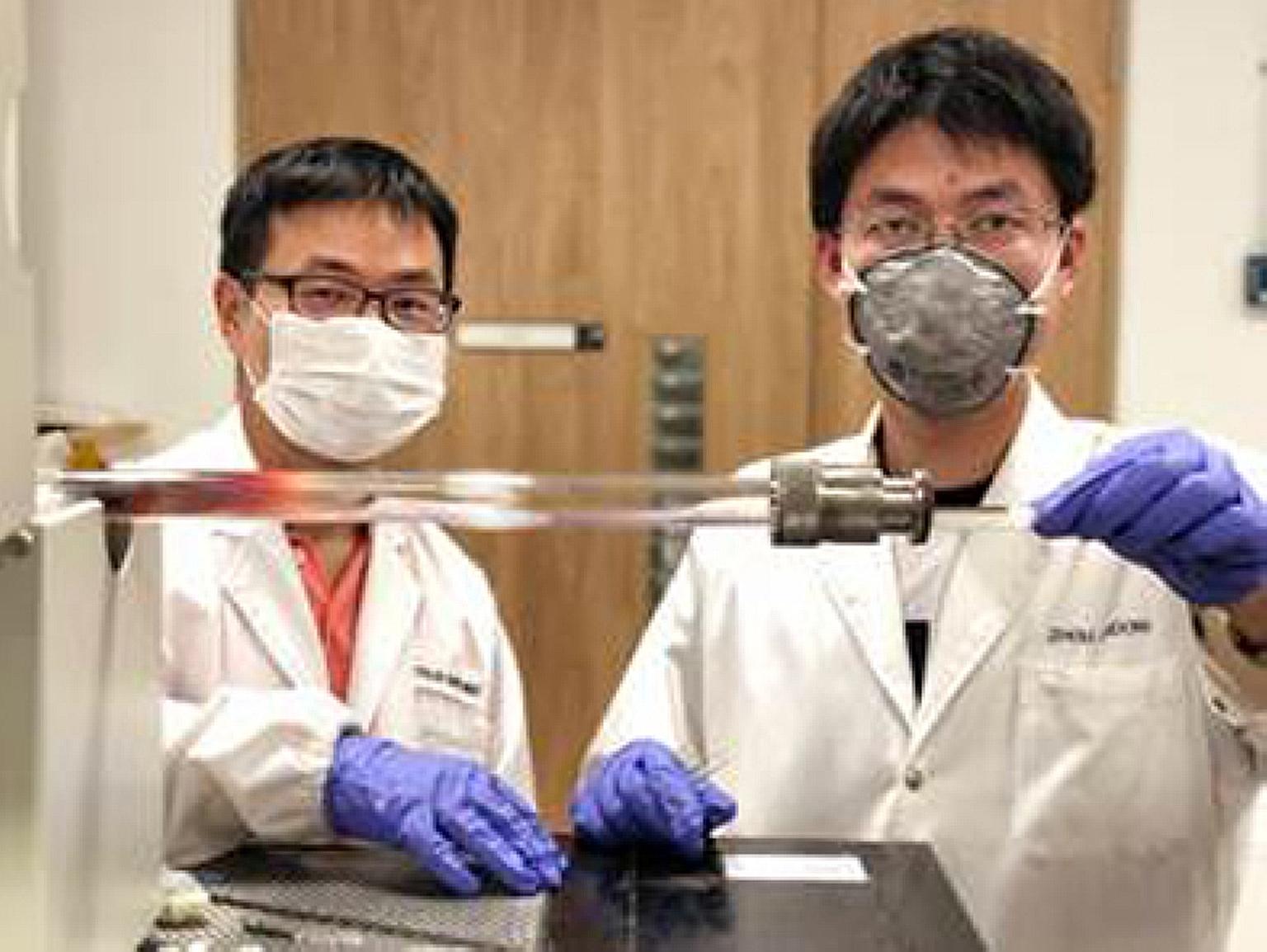Assistant Professor Liu Zheng (left) and Dr Zhou Jiadong insert a ceramic boat, containing salt mixed with other components used to make transition-metal chalcogenides, into a furnace.