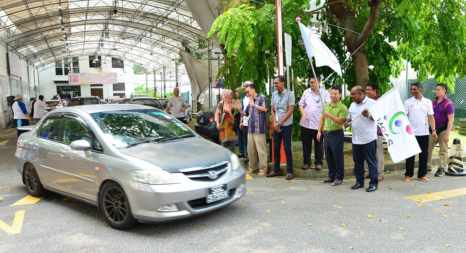Minister for Social and Family Development, Mr Desmond Lee (in green), flagging off cars at yesterday's Meals On Wheels event organised by Darul Arqam Singapore, also known as the Muslim Converts' Association of Singapore (MCAS). With him, holding th