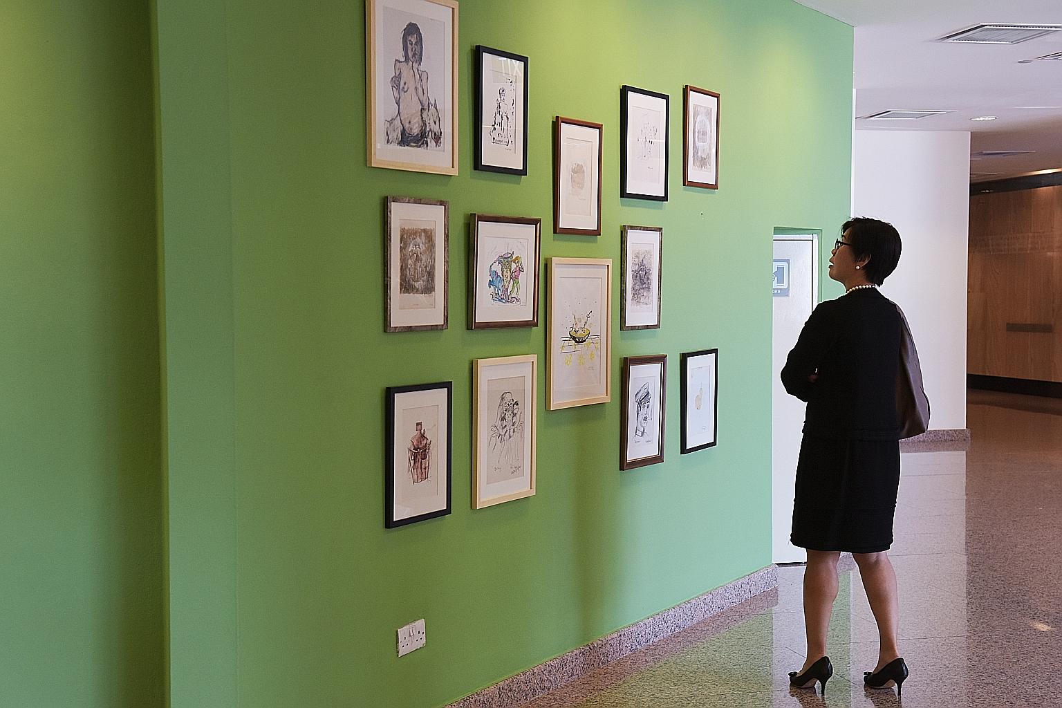 A visitor to the Esplanade looking at the artworks on the wall where Vincent Leow's controversial piece had been displayed, now an empty space between the two drawings at the extreme right of the wall.