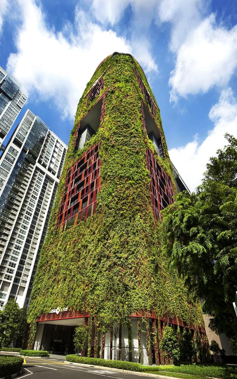 The 27-storey Oasia Hotel Downtown features a plant-covered facade of red and green and outdoor communal spaces along its height.