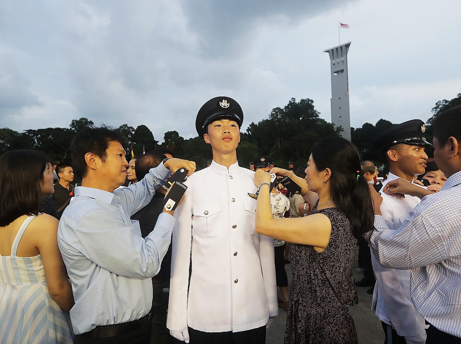 Businessman Tan Boon Poh and his wife, Madam Yu Shui Ping, 51, pinning on the uniform of their son, Second Lieutenant Gordon Tan, epaulettes bearing his rank.