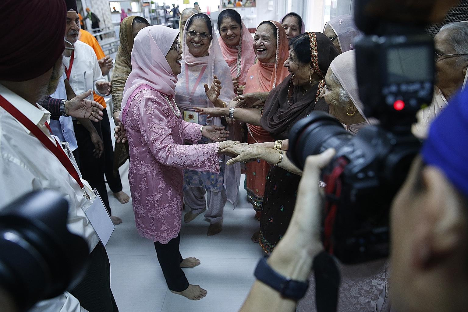 President Halimah Yacob being greeted by members of the Sikh community yesterday during Sri Guru Singh Sabha Singapore's 100th anniversary celebrations.