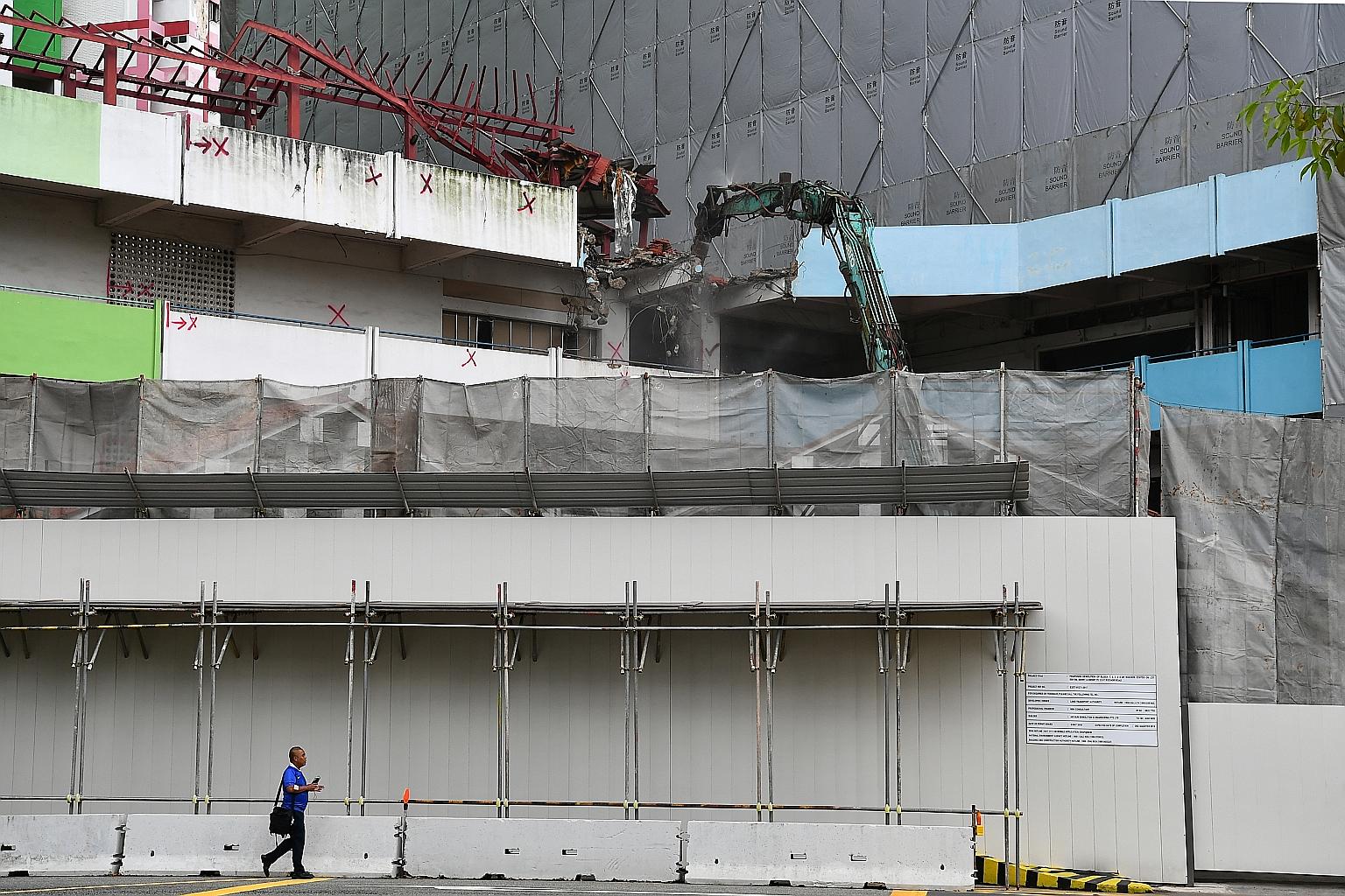 An excavator tore down parts of the iconic Rochor Centre yesterday, kicking off a demolition process that will last until next April. Some former residents made a trip to the four-block public housing estate, braving the heavy rain, to watch the work