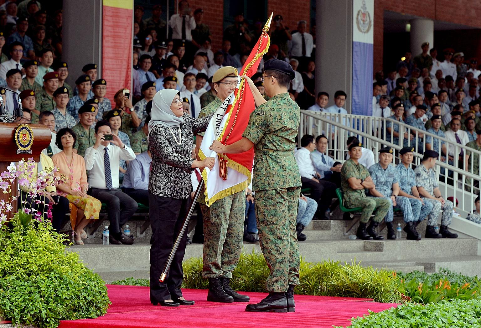 Colonel Paul Cheak, Chief Army Intelligence Officer, receiving the new Regimental Colours from President Halimah Yacob on behalf of the Headquarters Army Intelligence, as the Singapore Armed Forces (SAF) commemorated SAF Day at the Safti Military Ins