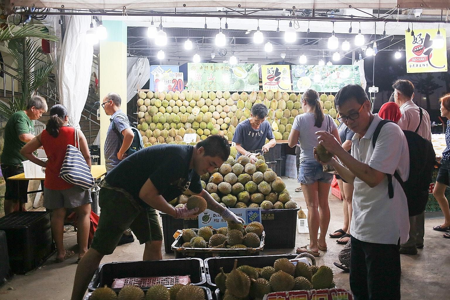 Mr Sky Teo (foreground, left), stall manager of Durian Fullhouse near Kovan market and food centre, said sales may not increase even though he is bringing in 30 55kg cartons of durians a day.