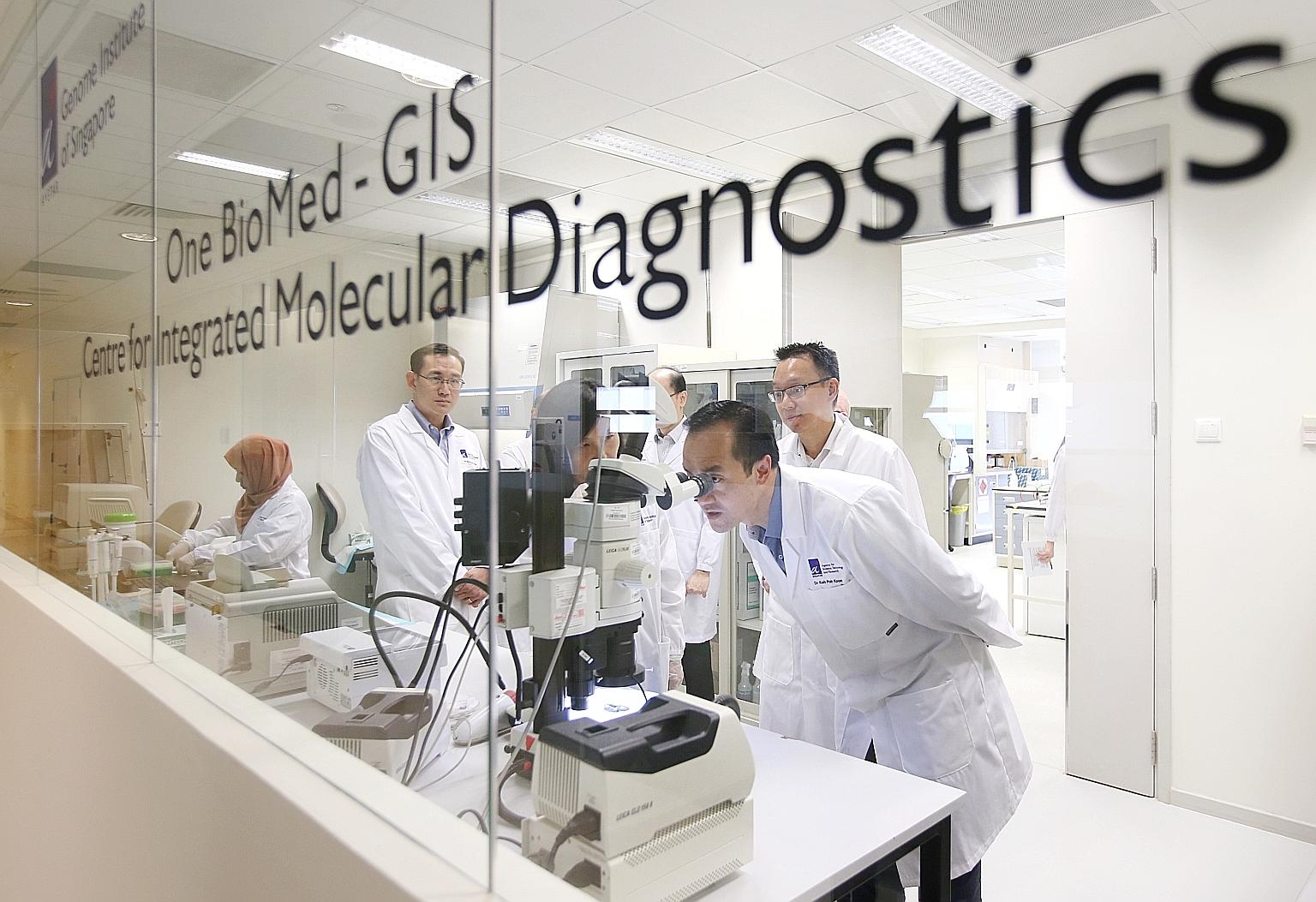 One BioMed founder Park Mi-kyoung explaining her start-up's work to Senior Minister of State for Trade and Industry Koh Poh Koon as he looks through a microscope at the Genome Institute of Singapore.