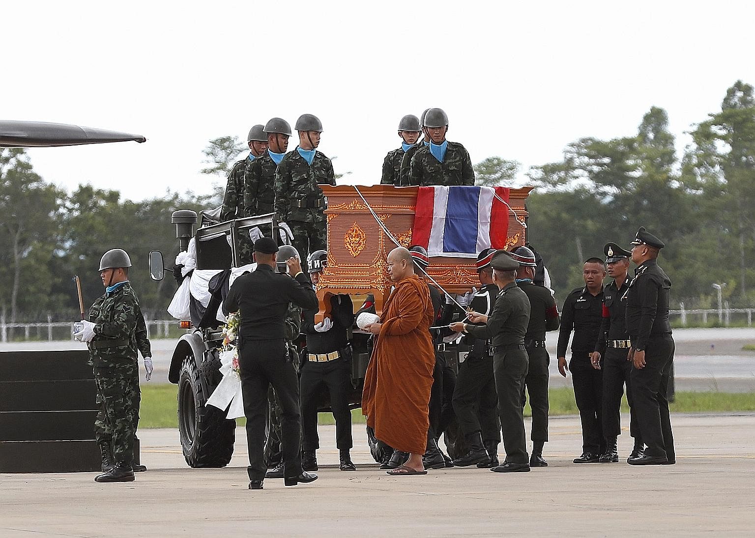 Left: A Thai Buddhist monk leading a military honour guard carrying the coffin of former Thai navy Seal diver Saman Kunan (above) at Mae Fah Luang international airport in Chiang Rai yesterday.