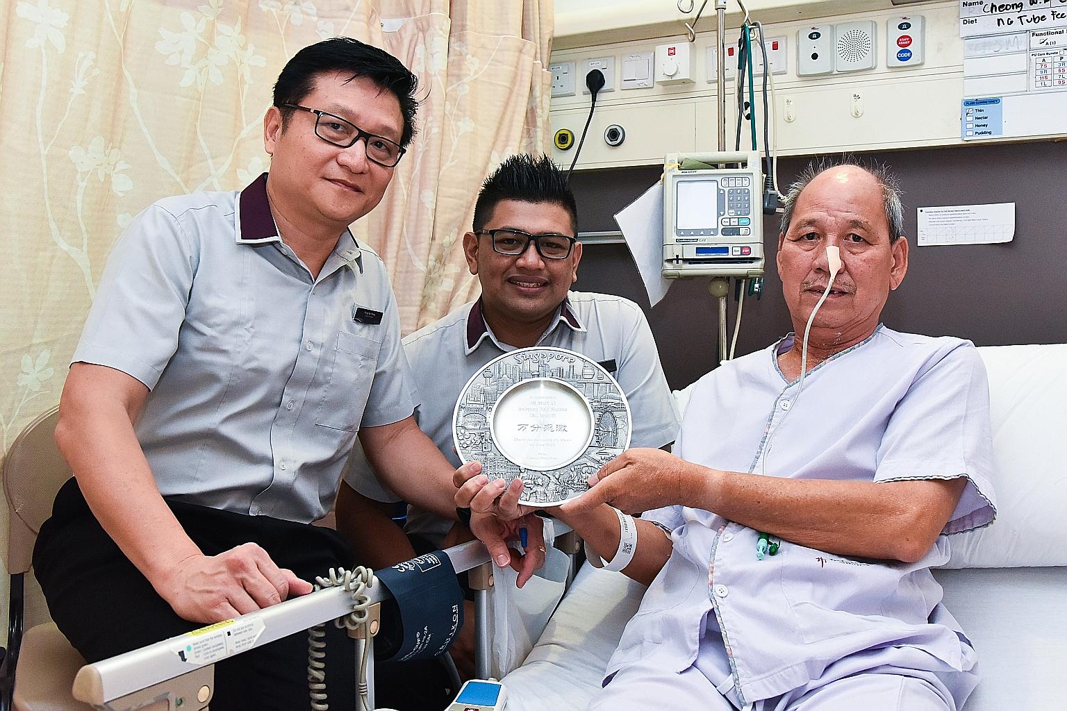 Station manager Fong Sai Weng and assistant station manager Abdul Azim Abdul Azizam visiting Mr Cheong Weng Kuen in hospital on Friday. Mr Cheong made a plaque and presented it to the SBS Transit duo to thank them.