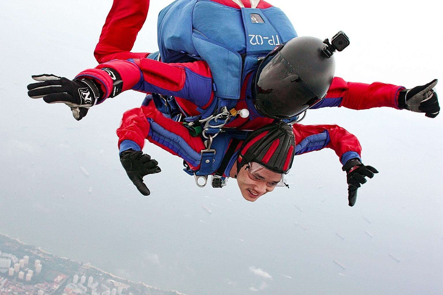 The Straits Times photojournalist Mark Cheong (bottom) putting nerves aside for a tandem jump with Red Lions First Warrant Officer (1WO) Dave Chong last Monday. 	The jump took place at Paya Lebar Air Base, where Mr Cheong went through a quick trainin