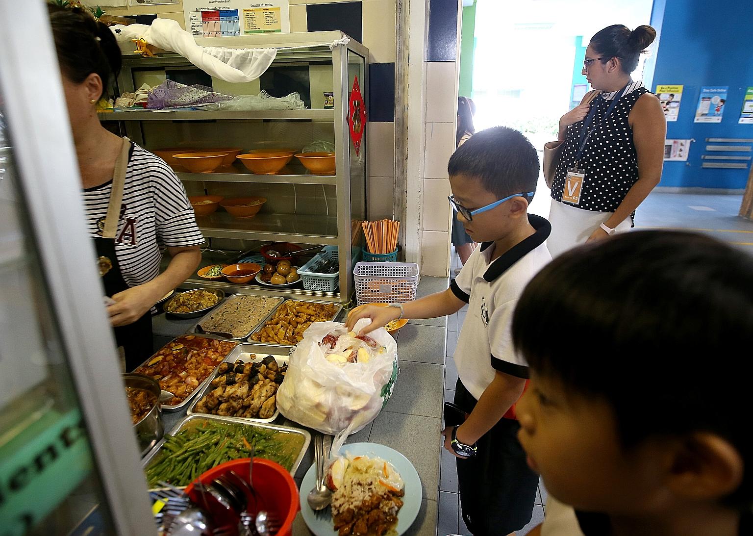 Da Qiao Primary pupil Joe Lee takes a free slice of apple from a canteen stall during recess. The school has put healthier options on the menu since 2016, when it joined HPB's Healthy Meals in Schools programme.
