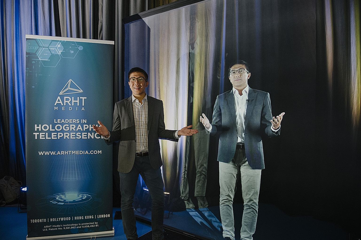 ARHT Media general manager Lincoln Cheung beside a hologram projection of himself. The firm's hologram technology allows speakers and performers to be projected from a distant place using a transparent screen, so that they can engage and interact wit