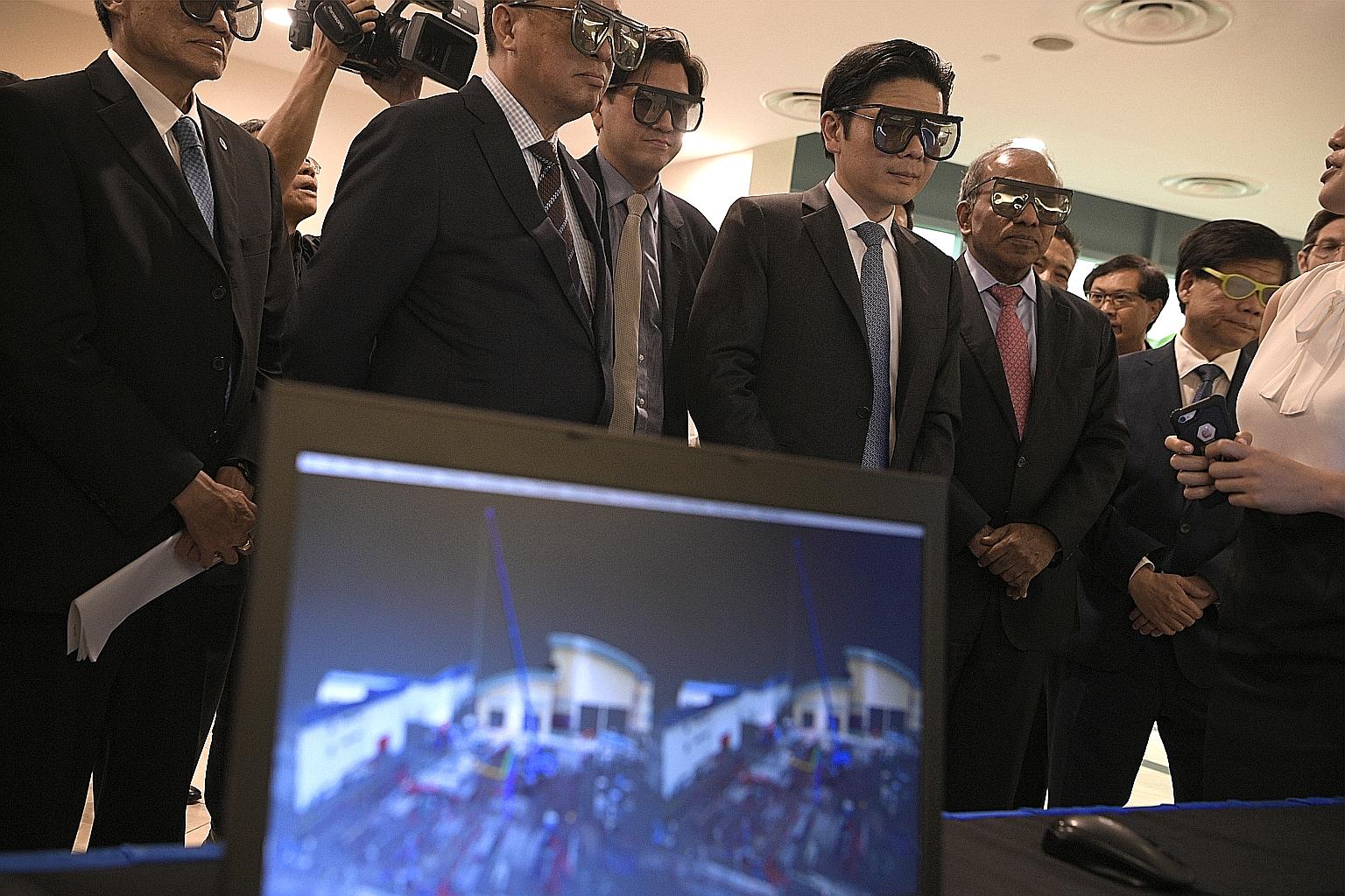 National Development Minister Lawrence Wong (fourth from left) wearing 3D glasses to look at a screen with a building scanned using a digitisation technique, after the launch of the SJ-NTU Corporate Lab yesterday.