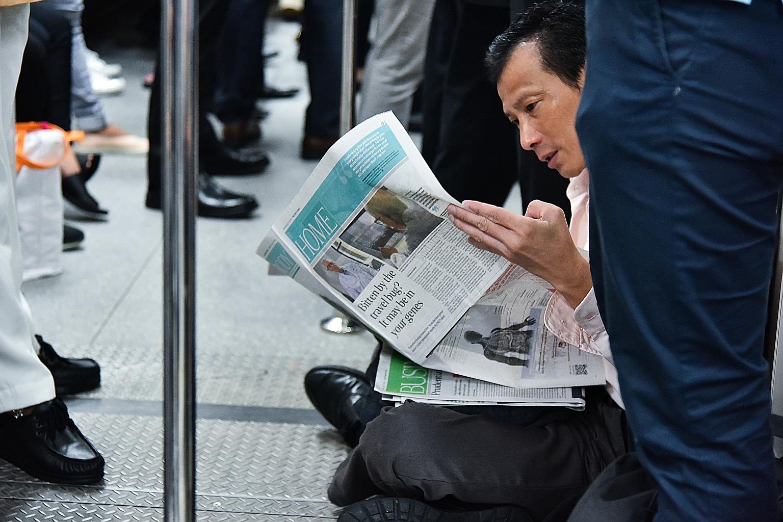 A commuter on an MRT train reading The Straits Times, which was launched in 1845.
