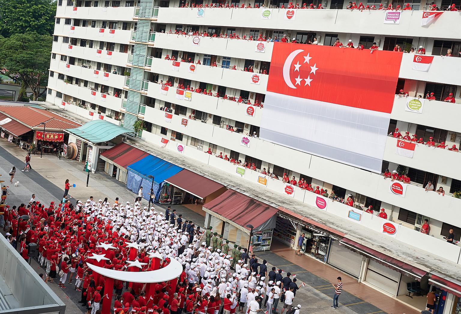 Bedok residents dressed in red and white form a human flag between Blocks 16 and 18 on Bedok South Road, mirroring a giant 12m-by-8m Singapore flag hung on the facade of Block 18. The block was also decorated with slogans such as Majulah Singapura as