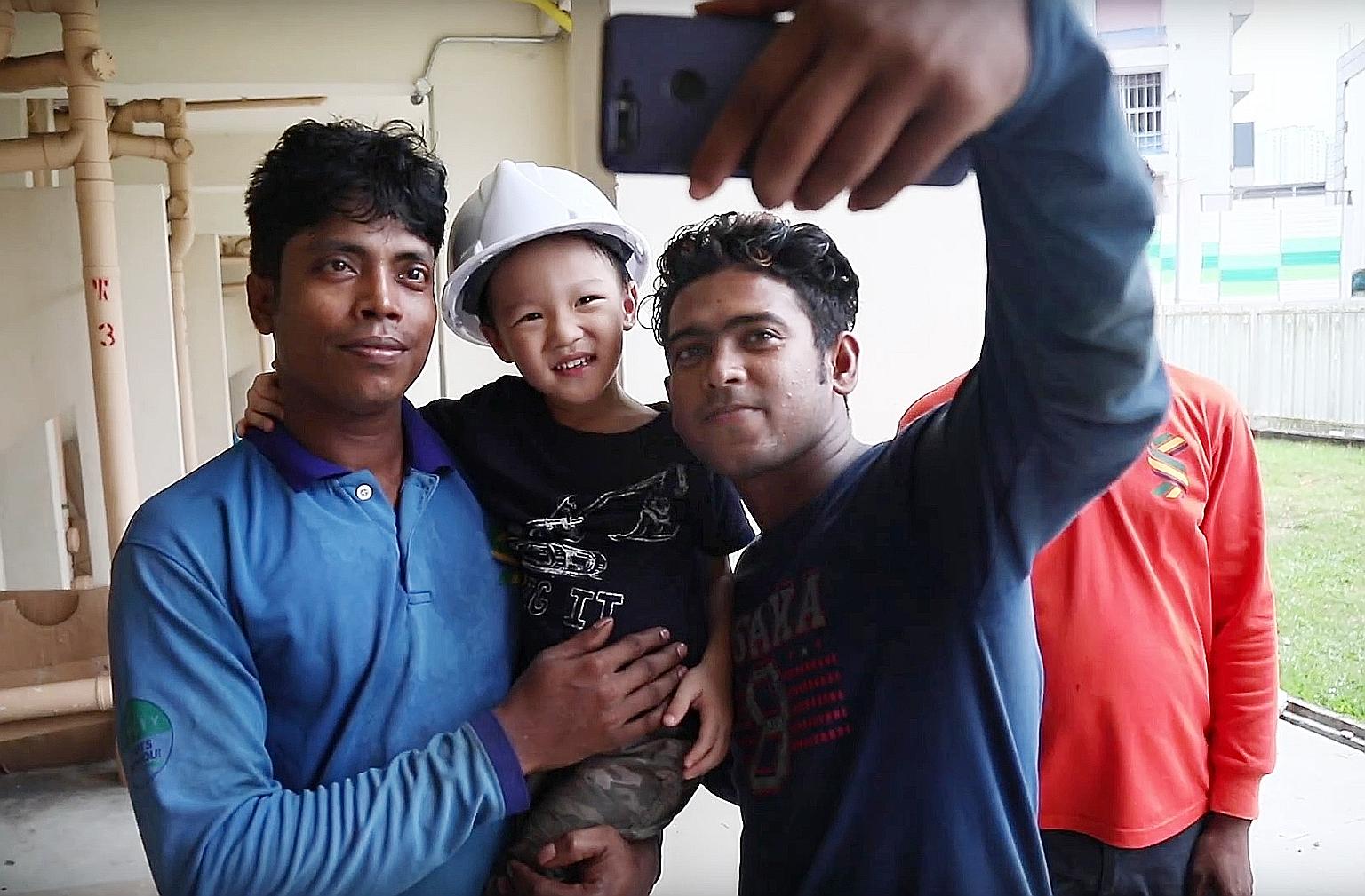 Jake in the arms of "Red Helmet Uncle", one of the foreign workers he befriended after he saw them carrying out upgrading works near his home.