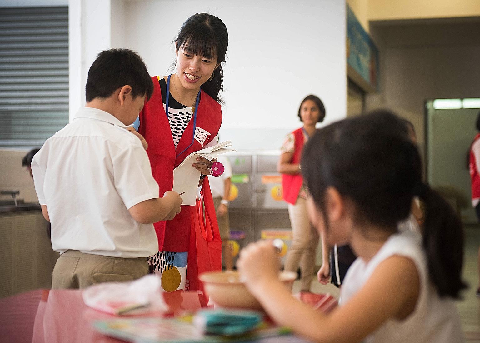 Food From The Heart volunteer Charlene Teo handing out pens and stickers to pupils at Kong Hwa School at the launch of this year's Clean Plate Campaign yesterday. This year, 65 primary schools are taking part in the campaign which aims to reduce food