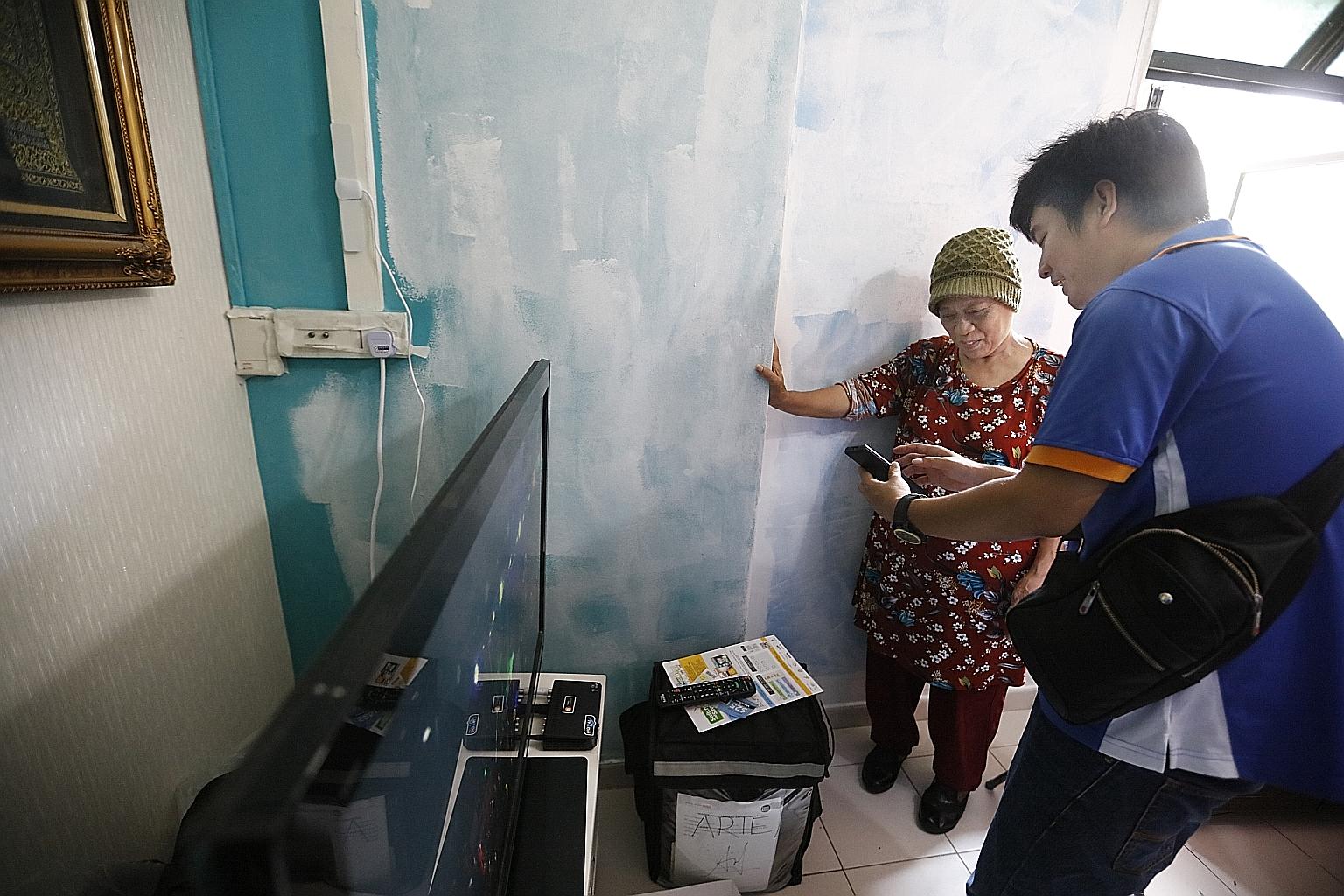 Ms Aminah Lendi, who lives in a rental flat, with a volunteer who is educating residents on the benefits of changing to LED lights.