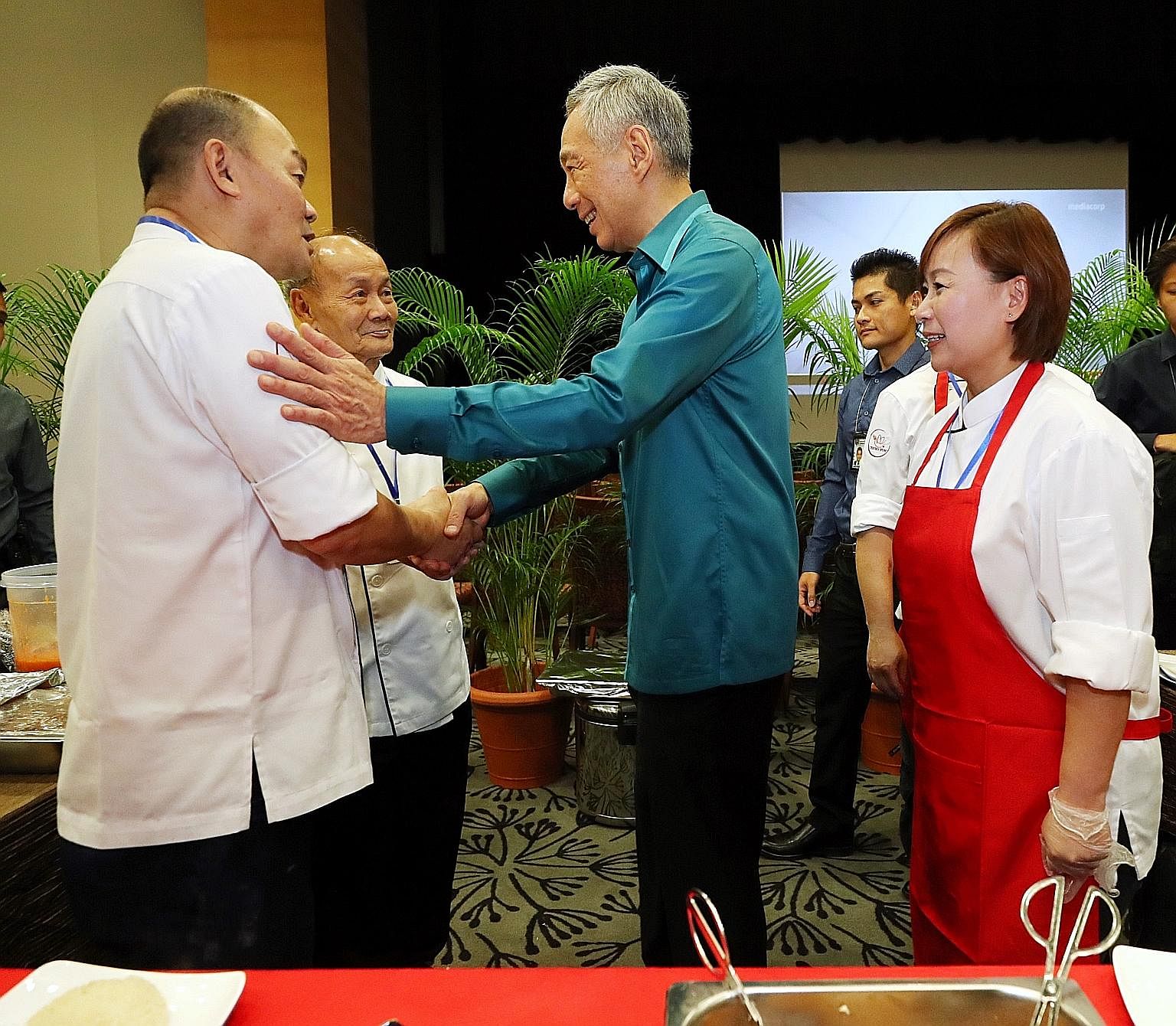 Prime Minister Lee Hsien Loong with Mr Raymond Kiang (far left), 57, who sells chicken rice at Our Tampines Hub, his father Kiang Joon Toh, 70, one of the pioneer chefs who developed Chatterbox chicken rice at Mandarin Hotel, and sister Susan. Singap