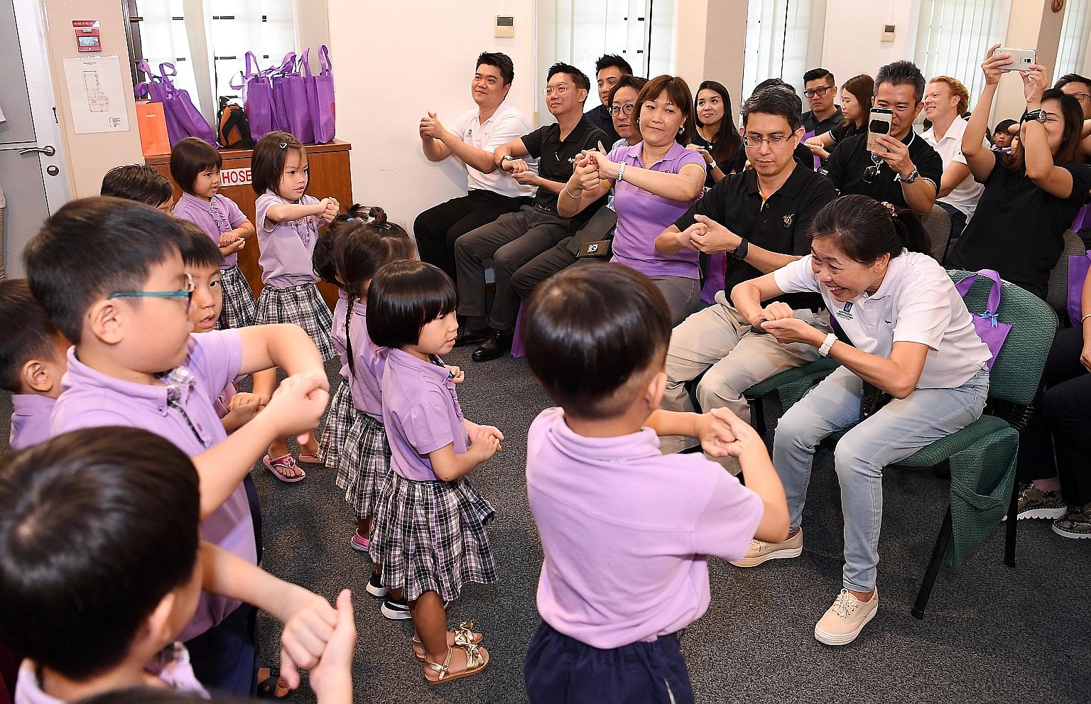 From right: RAS president Tan Puay Hoon, Associate Professor Muhammad Faishal Ibrahim and Ms Brands Ng, director of Cherie Hearts @ Charlton, joining in as the pre-schoolers put on a performance, showing how to wash their hands properly.