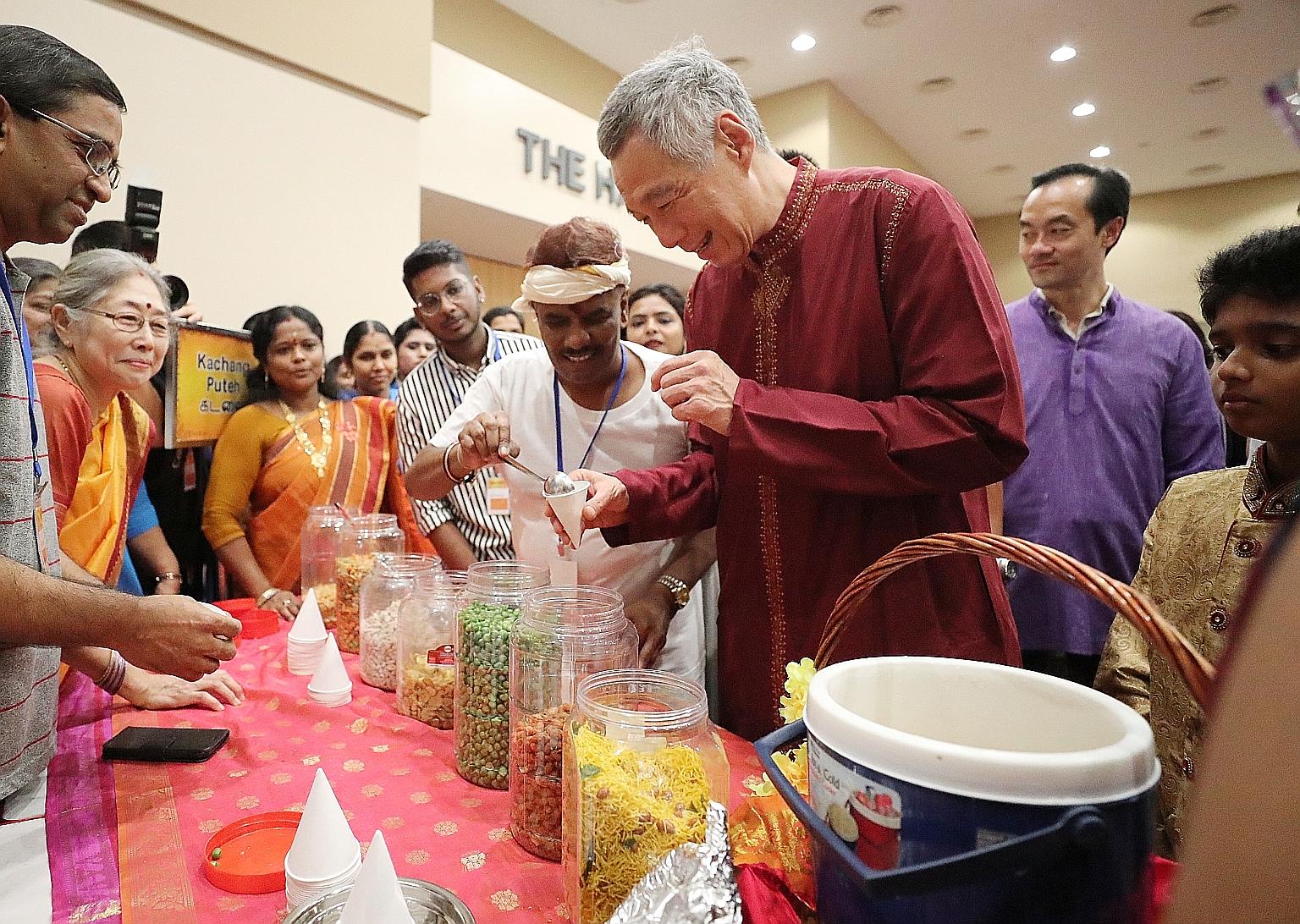 Prime Minister Lee Hsien Loong gets kacang putih, a traditional snack, from a stall at the Rhythms In Unity - Sangamam 2018 event, held at the Institute of Technical Education College Central campus. Behind him is Senior Minister of State for Trade a