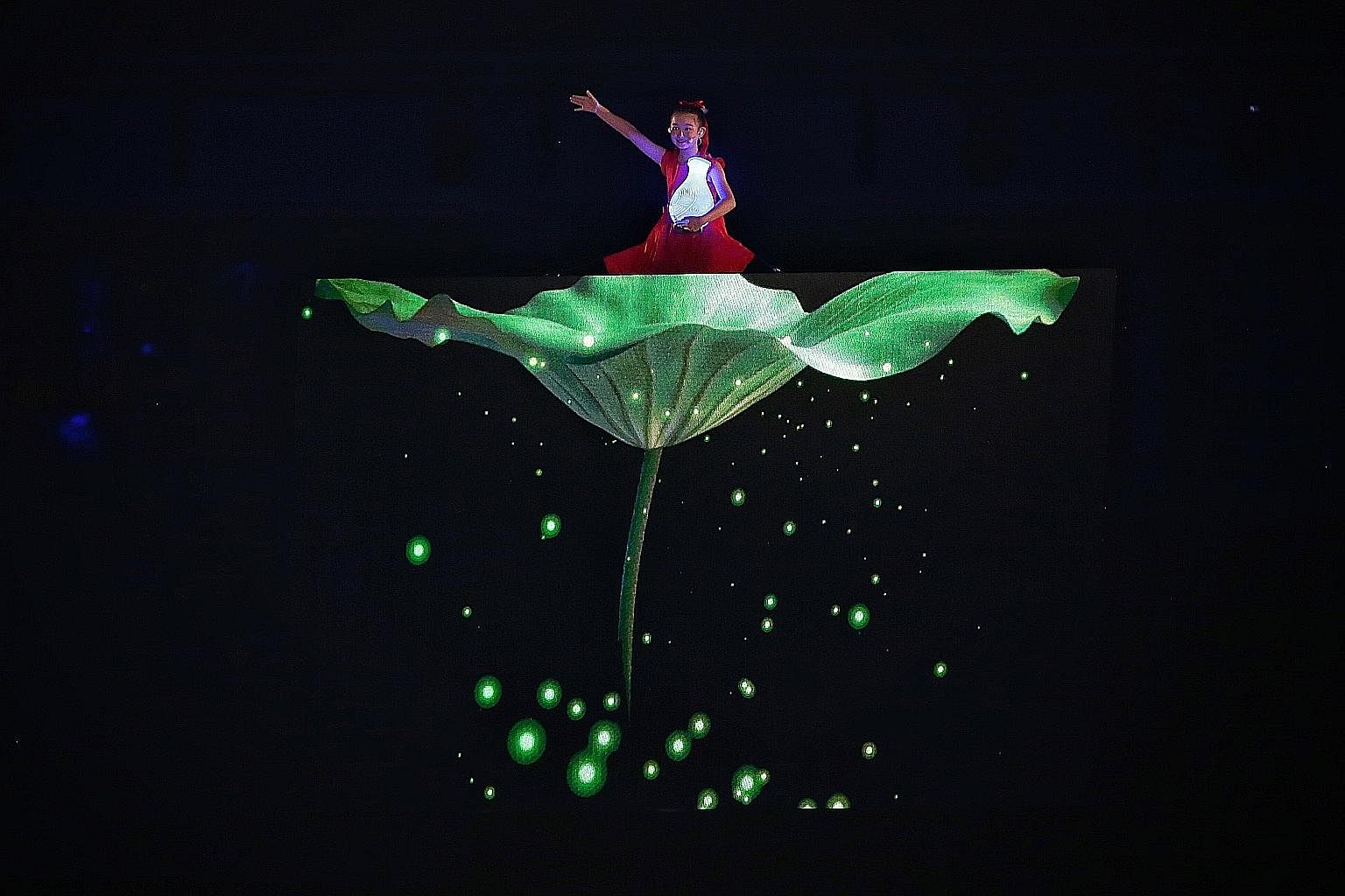 A young performer rises above the crowd with the announcement of Hangzhou as the host of the 2022 Asian Games during the closing ceremony of the 18th Asian Games in Jakarta. Thousands of athletes in ponchos marched in heavy rain at Gelora Bung Karno 