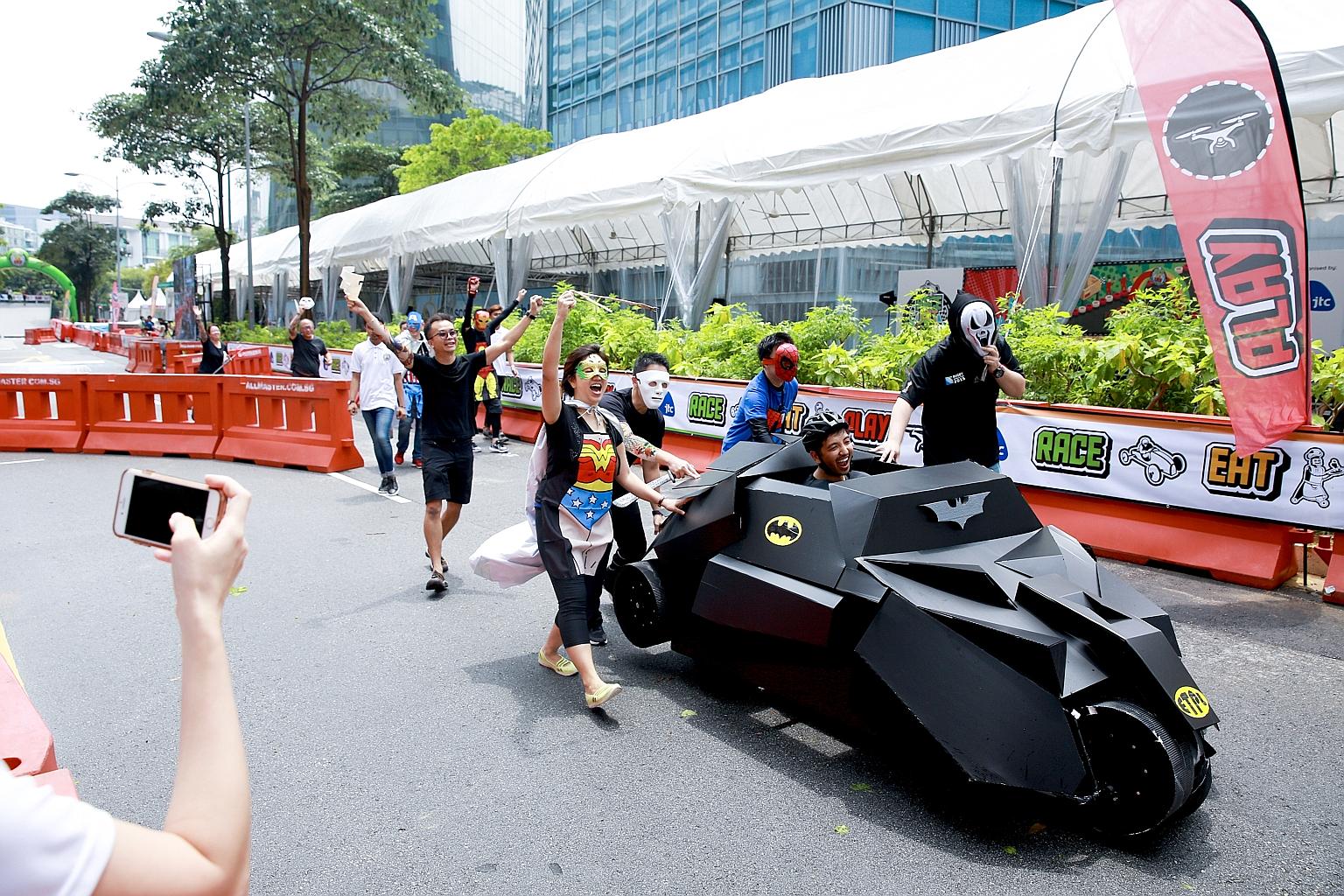 A*Star Exploit Technologies employees, dressed as DC and Marvel comics superheroes, banding together yesterday to push their soapbox "Batmobile" to the finish line.