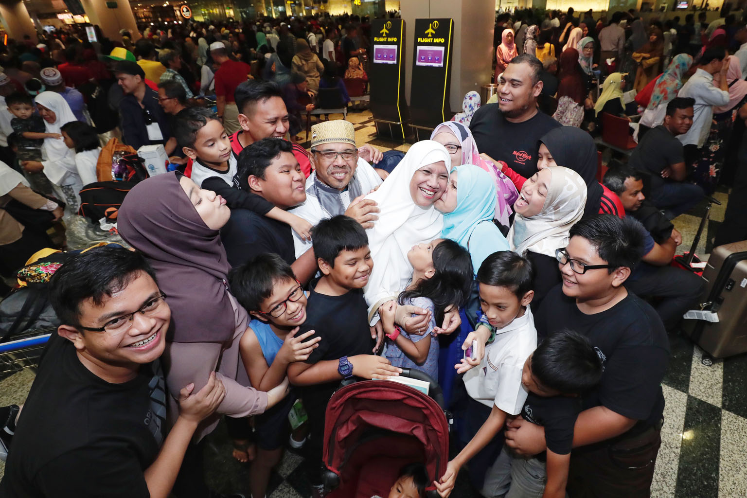 Returning Haj pilgrims Abdullah Ahmad (centre with a gold songkok), 63, and his wife Safiah Ahmad (in a white tudung), 60, receiving a group hug from their family members at Changi Airport Terminal 3 yesterday. The retirees were among more than 280 p