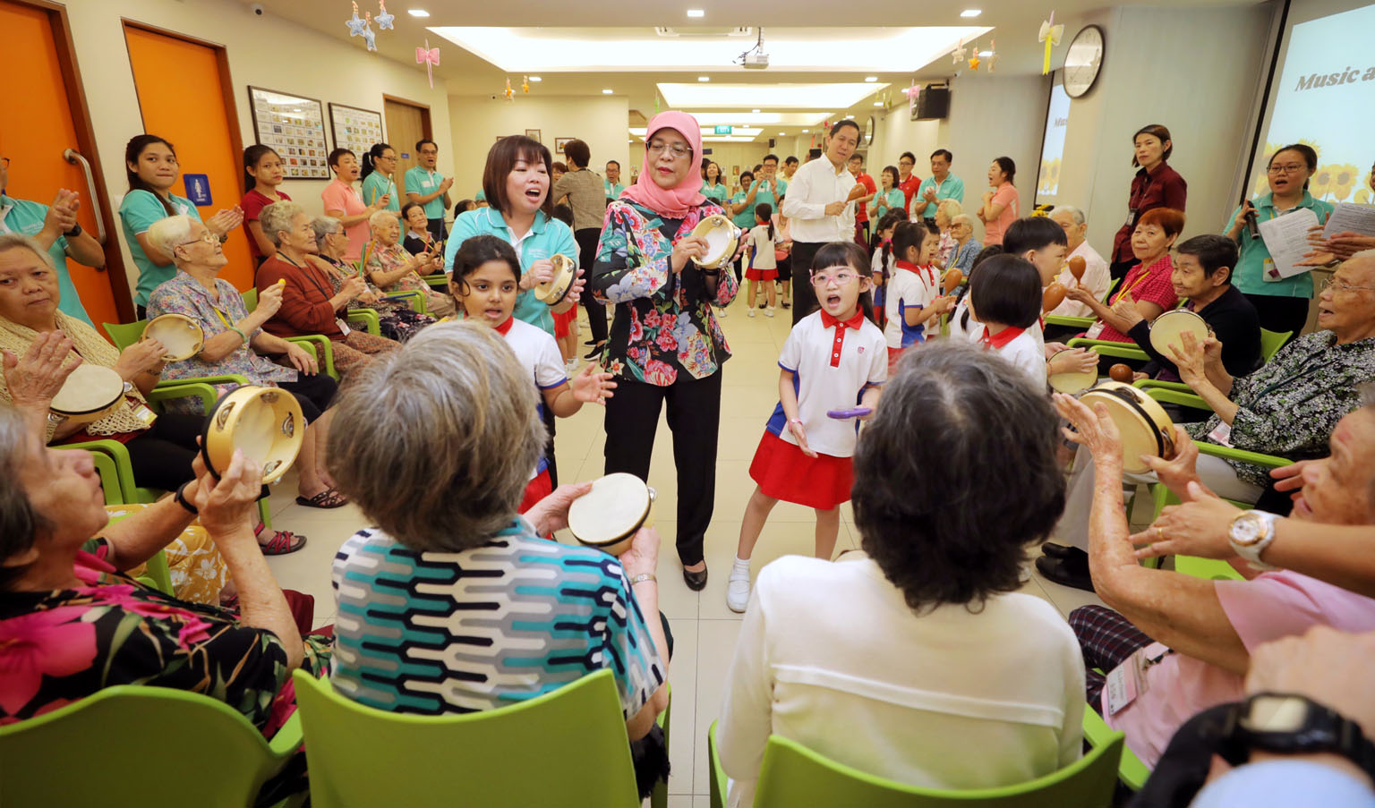 President Halimah Yacob (at centre) joined about 30 seniors and 21 kindergarten pupils at Sparkle Care @ Yew Tee for an activity-filled programme that promotes inter-generational understanding yesterday. Participants joined in with tambourines or oth