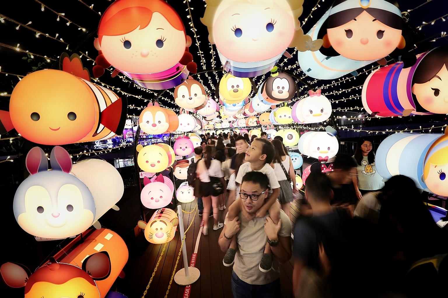 Six-year-old Gideon, riding on the shoulders of his father, Mr Michael Lee, 37, being drawn to the Disney Tsum Tsum lanterns at VivoCity's Sky Park yesterday. More than 2,000 of the lanterns are on display there until Sept 30, as part of the mall's M