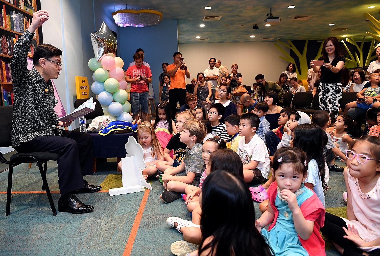 Finance Minister Heng Swee Keat reading to children about the life of Singaporean scientist Chou Loke Ming at the launch of the Asian Scientist Junior Book Series, a children's book series featuring six scientists from Asia.